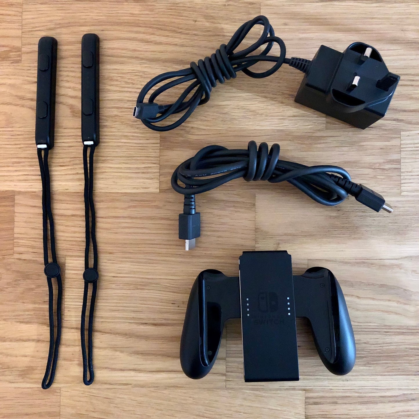 Nintendo Switch accessories including Joy-Con straps, HDMI cable, charger plug and Joy-Con grip laid out.