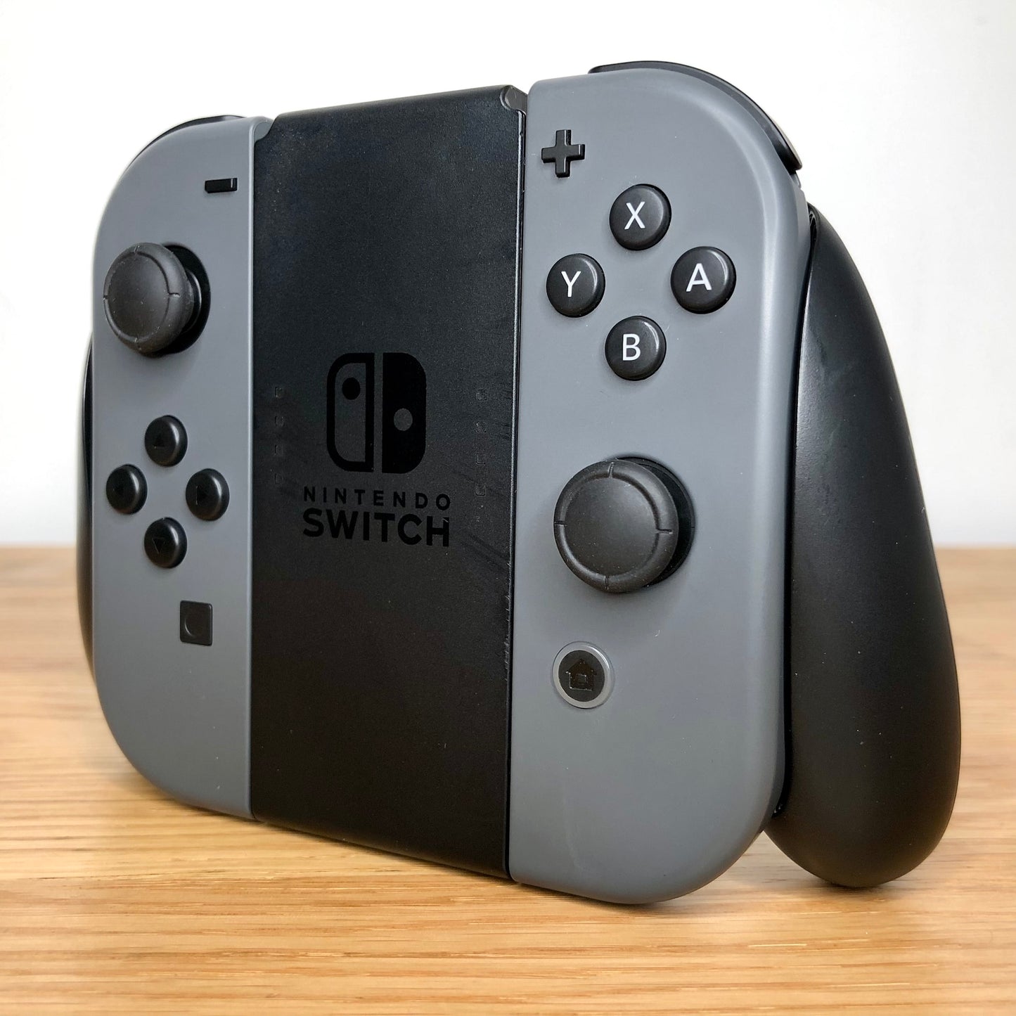 Angled left view of Joy-Con grip with grey Joy-Cons, showing all face buttons.