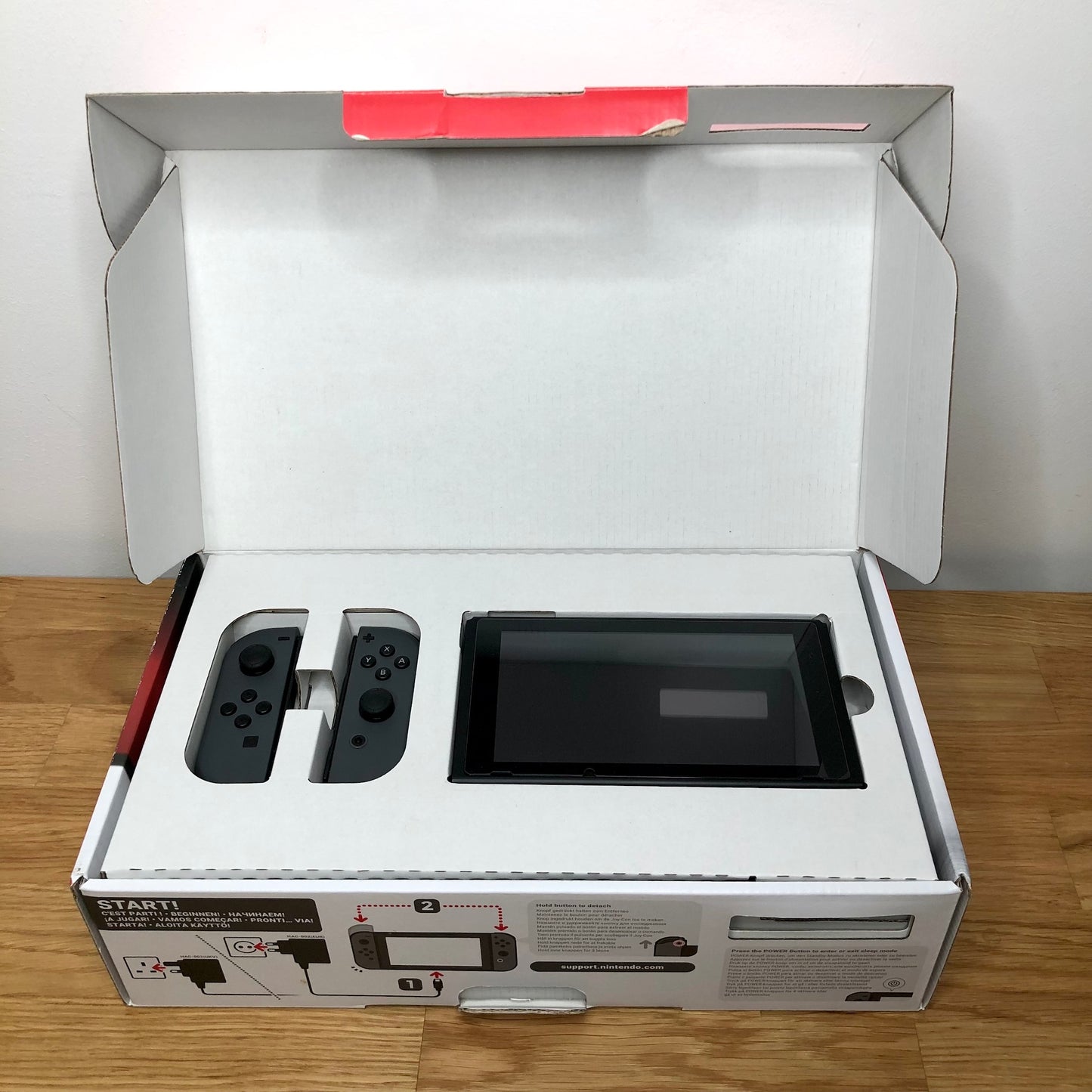 Nintendo Switch console in original box with lid open, showing console and Joy-Cons neatly packed in top tray.