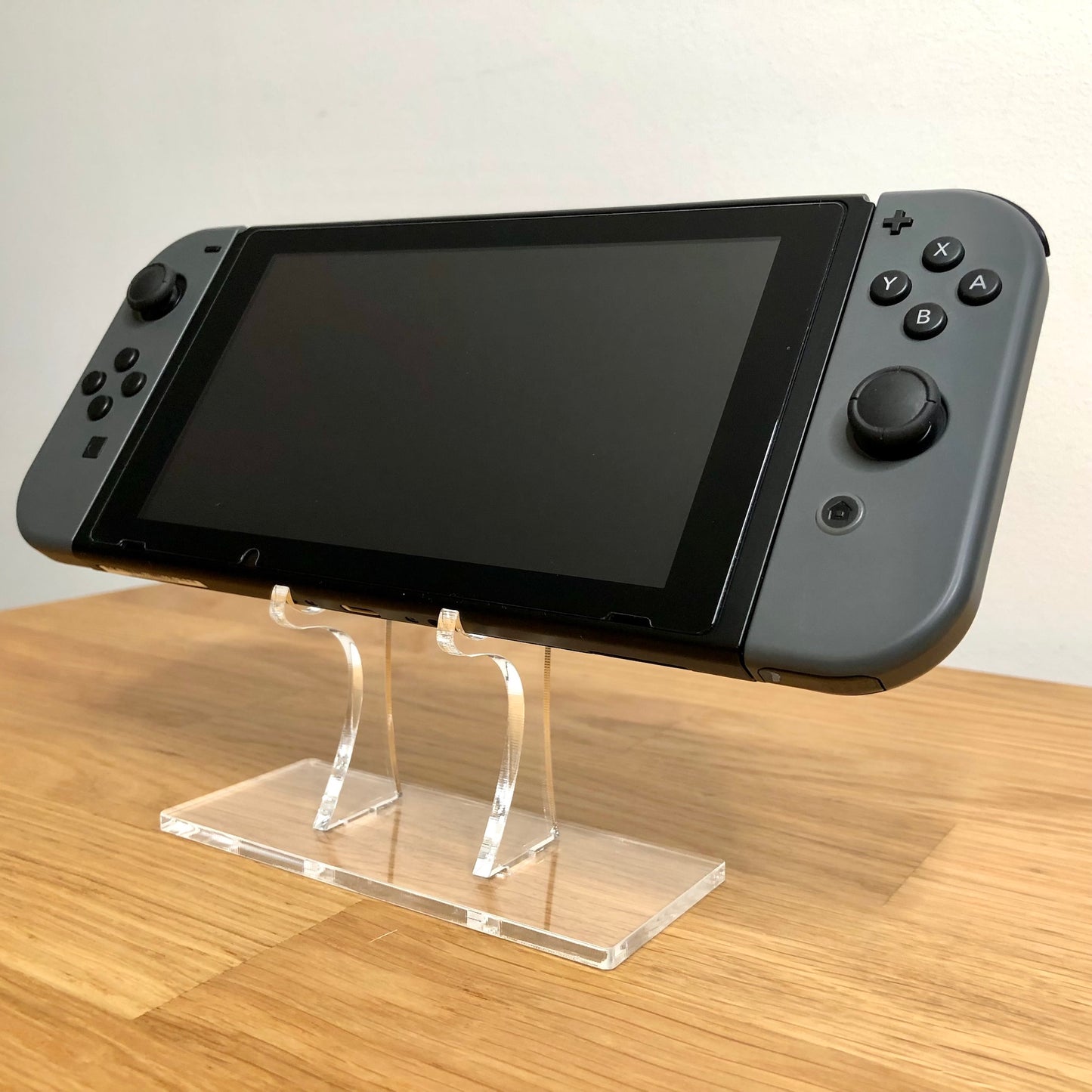 Angled front of Nintendo Switch with grey Joy-Cons, showing full face buttons, control sticks and screen.