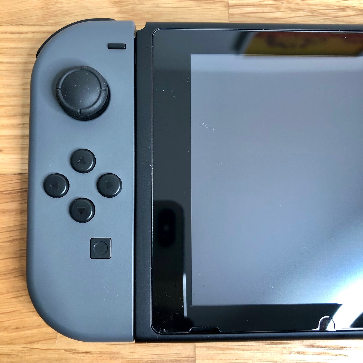 Close-up of grey left Joy-Con on Nintendo Switch, showing D-pad style buttons, stick and capture button.