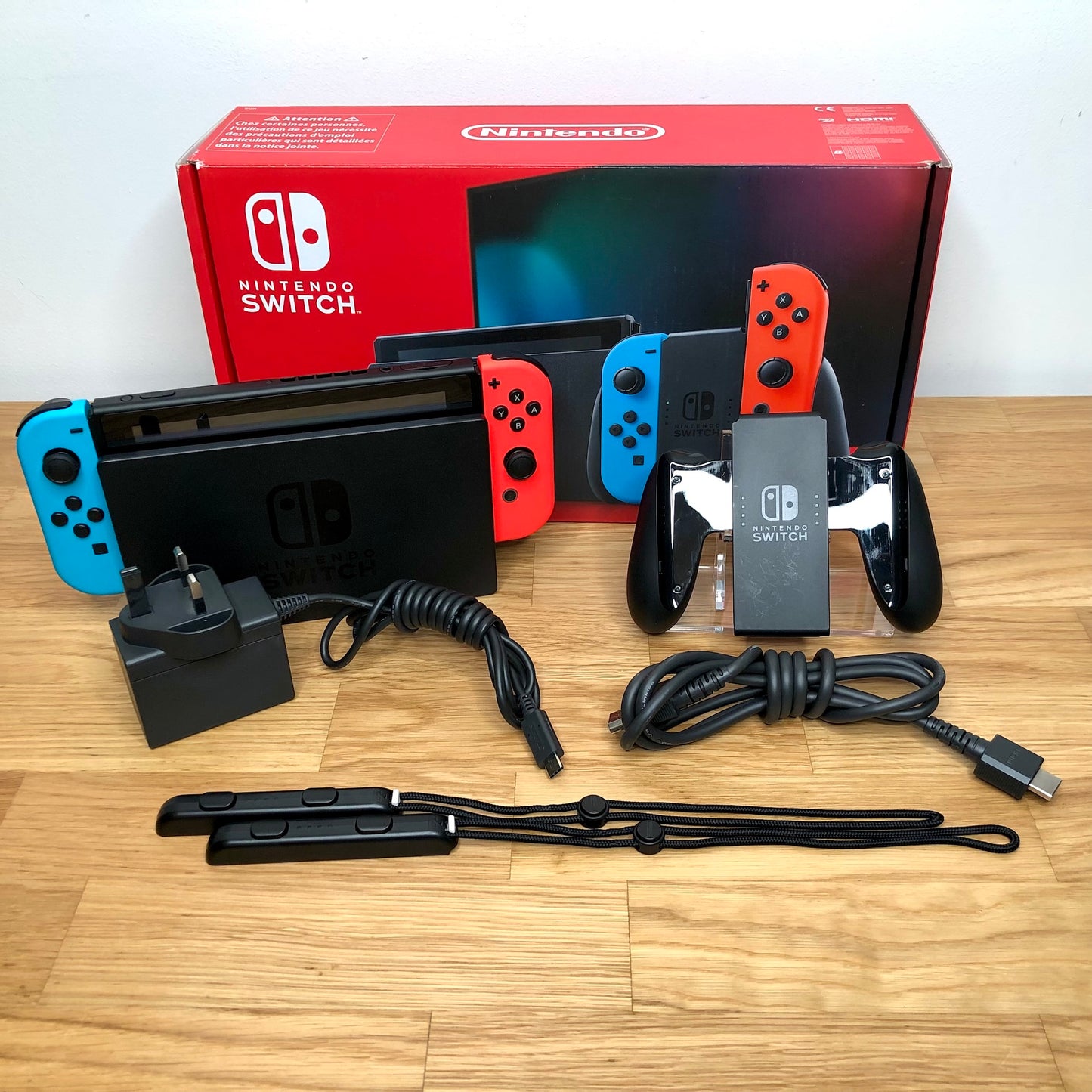 Nintendo Switch console with original box, Joy-Con grip, charger, HDMI cable and wrist straps shown.