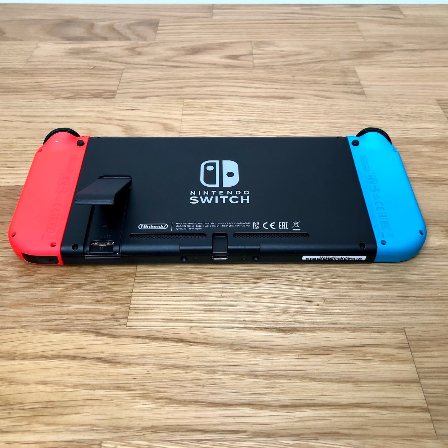 Rear of Nintendo Switch with kickstand open, showing logo, microSD card slot and dock connector.