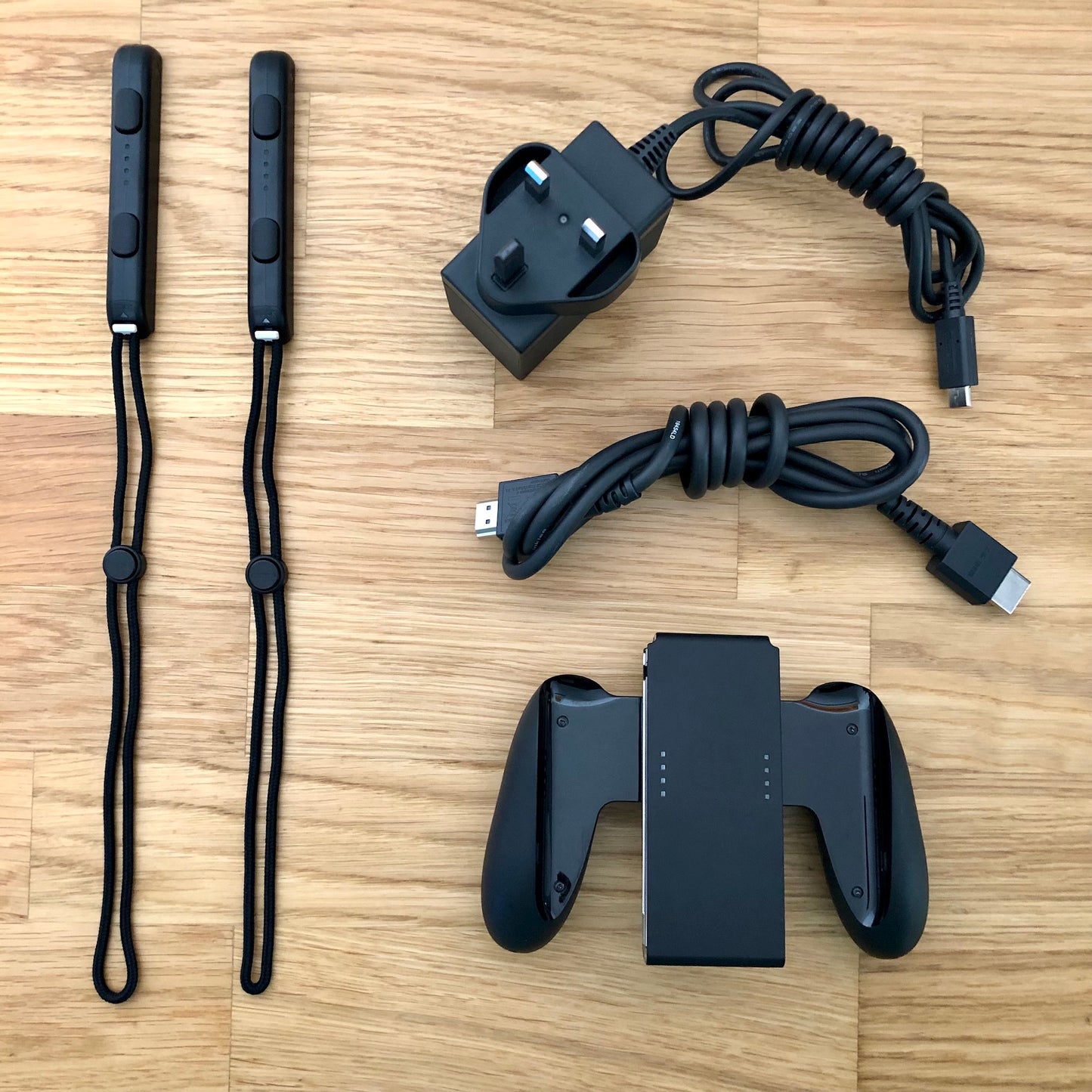 Nintendo Switch accessories including Joy-Con straps, HDMI cable, charger plug and Joy-Con grip laid out.