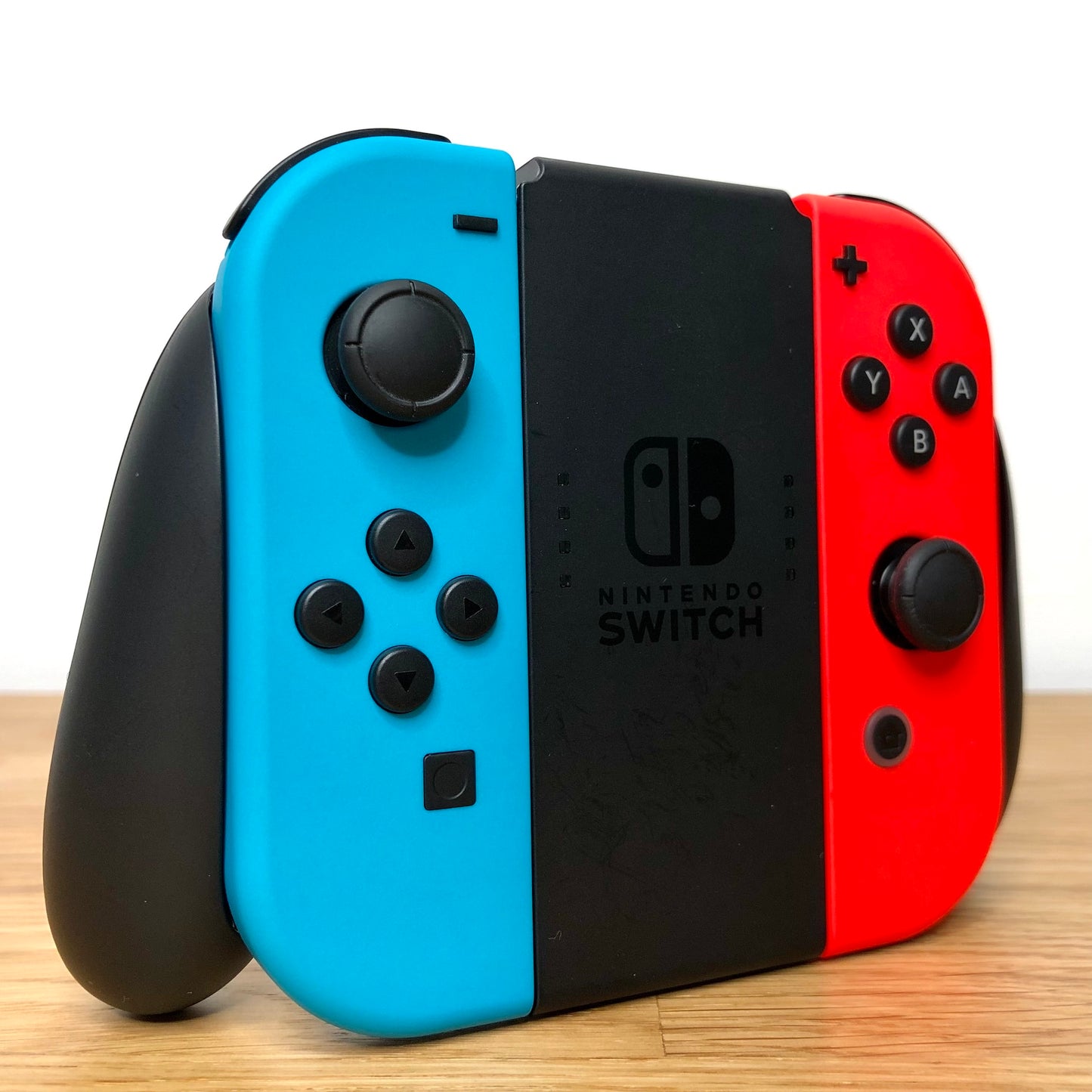 Angled left view of Joy-Con grip with neon Joy-Cons, showing all front facing buttons.