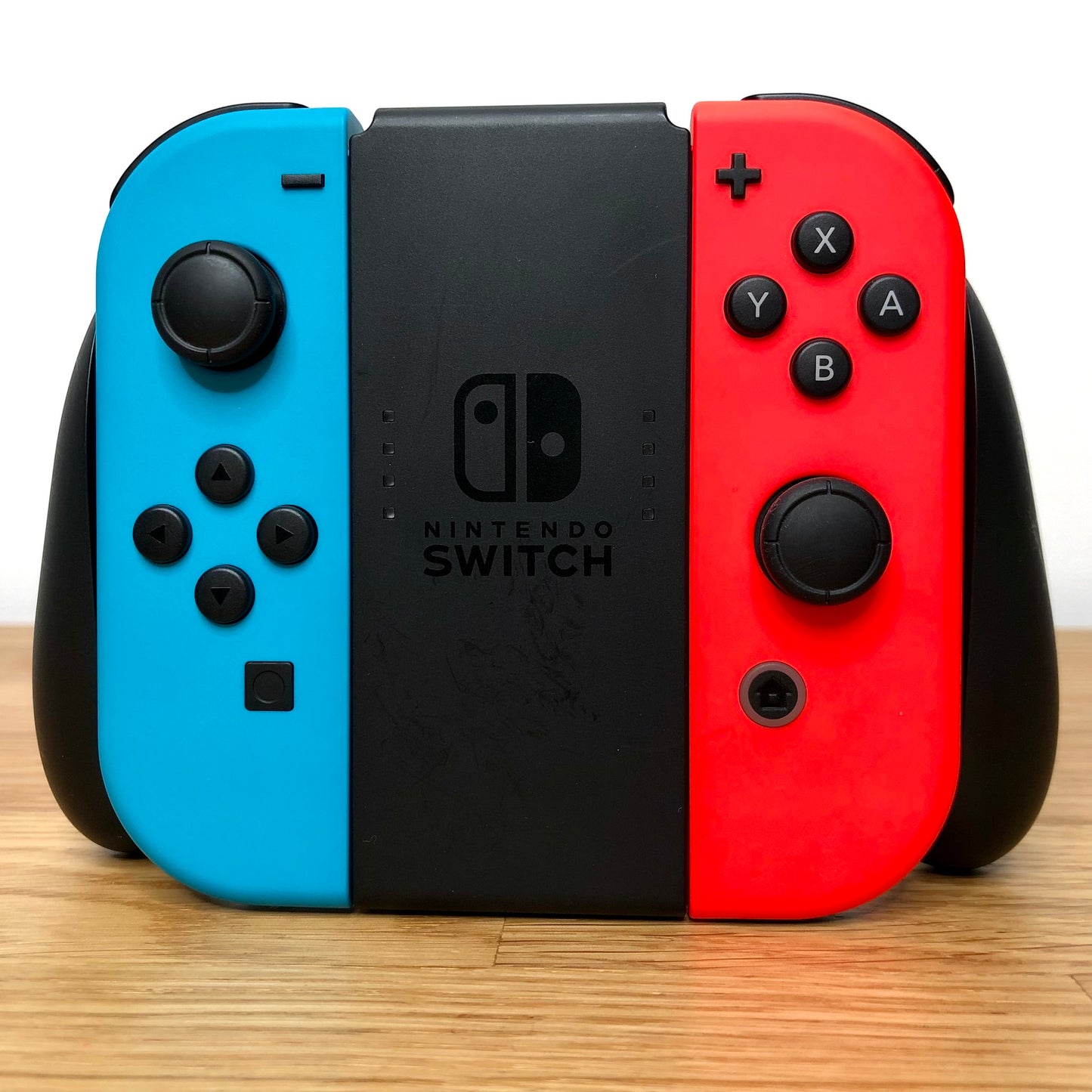 Front view of Joy-Con grip with neon red and blue Nintendo Switch Joy-Cons, showing all front facing buttons.