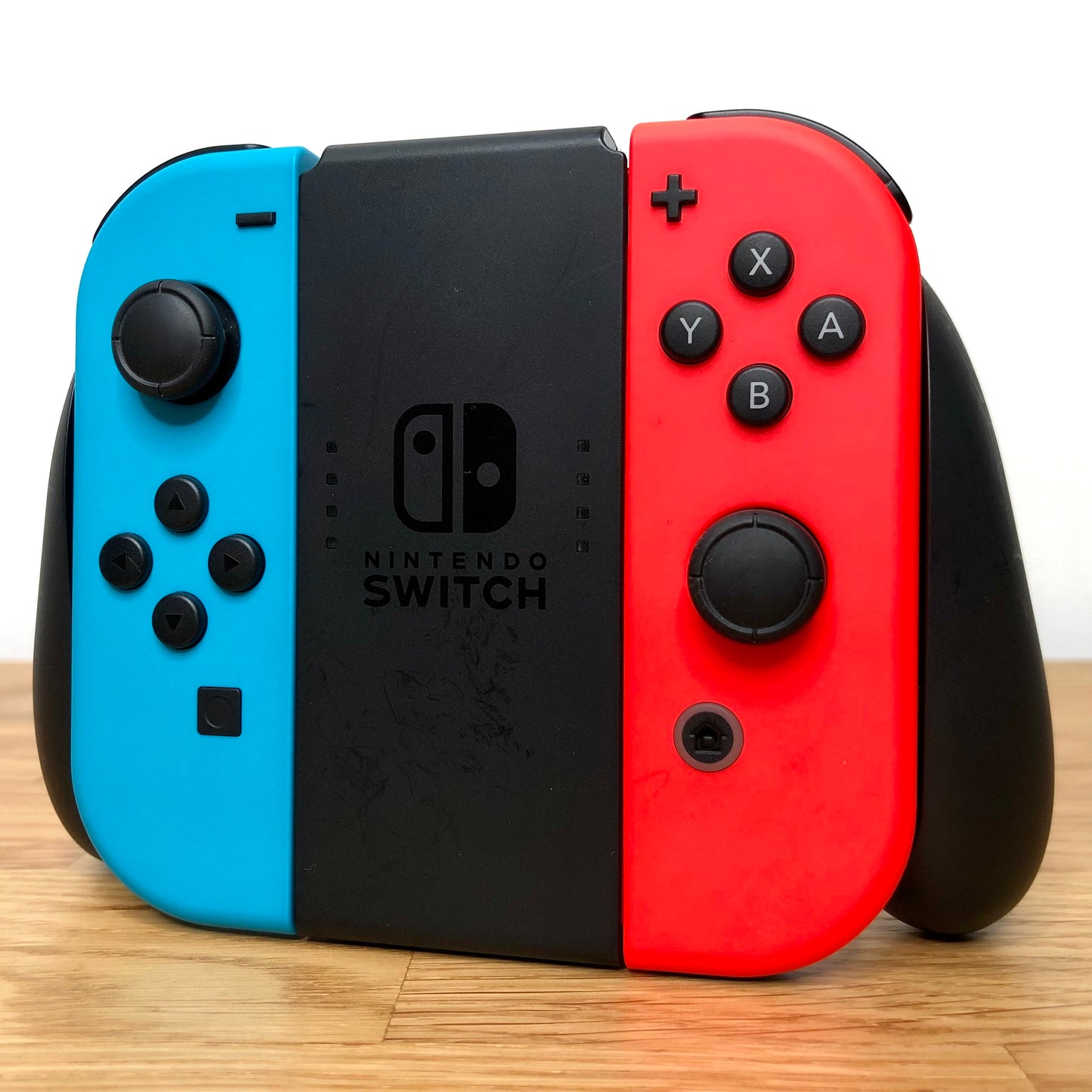 Angled right view of Joy-Con grip with neon Joy-Cons, showing all front facing buttons.