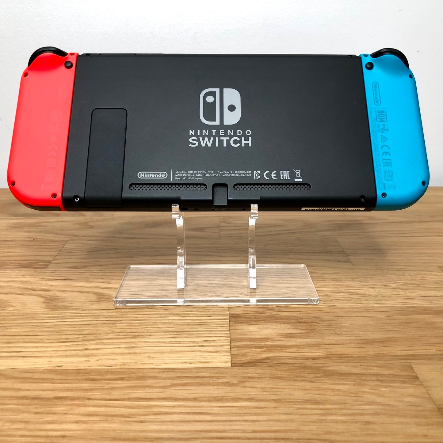 Back of Nintendo Switch console with red and blue Joy-Cons attached, showing logo, kickstand and trigger buttons.