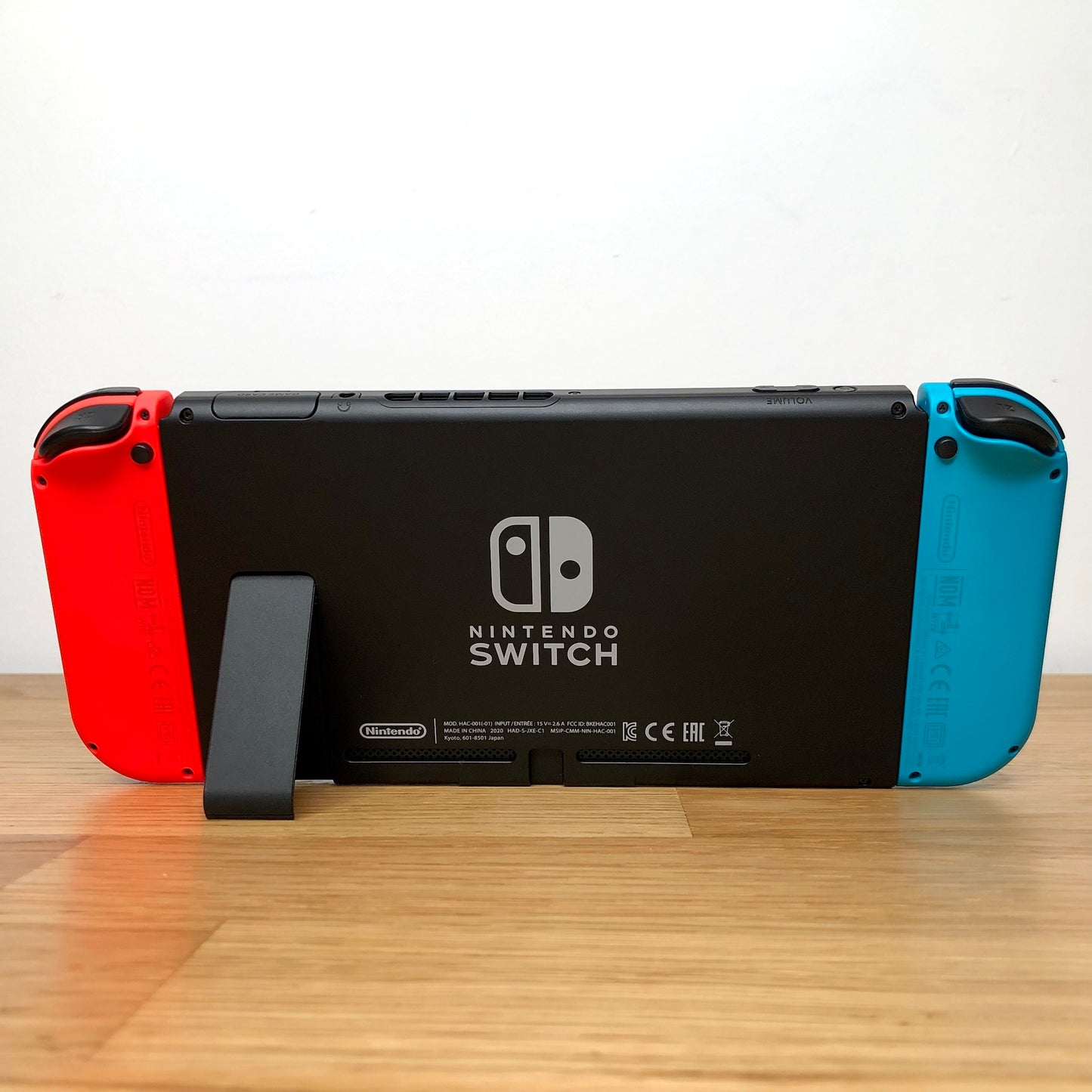 Back of Nintendo Switch console with red and blue Joy-Cons attached, showing logo, kickstand and trigger buttons.