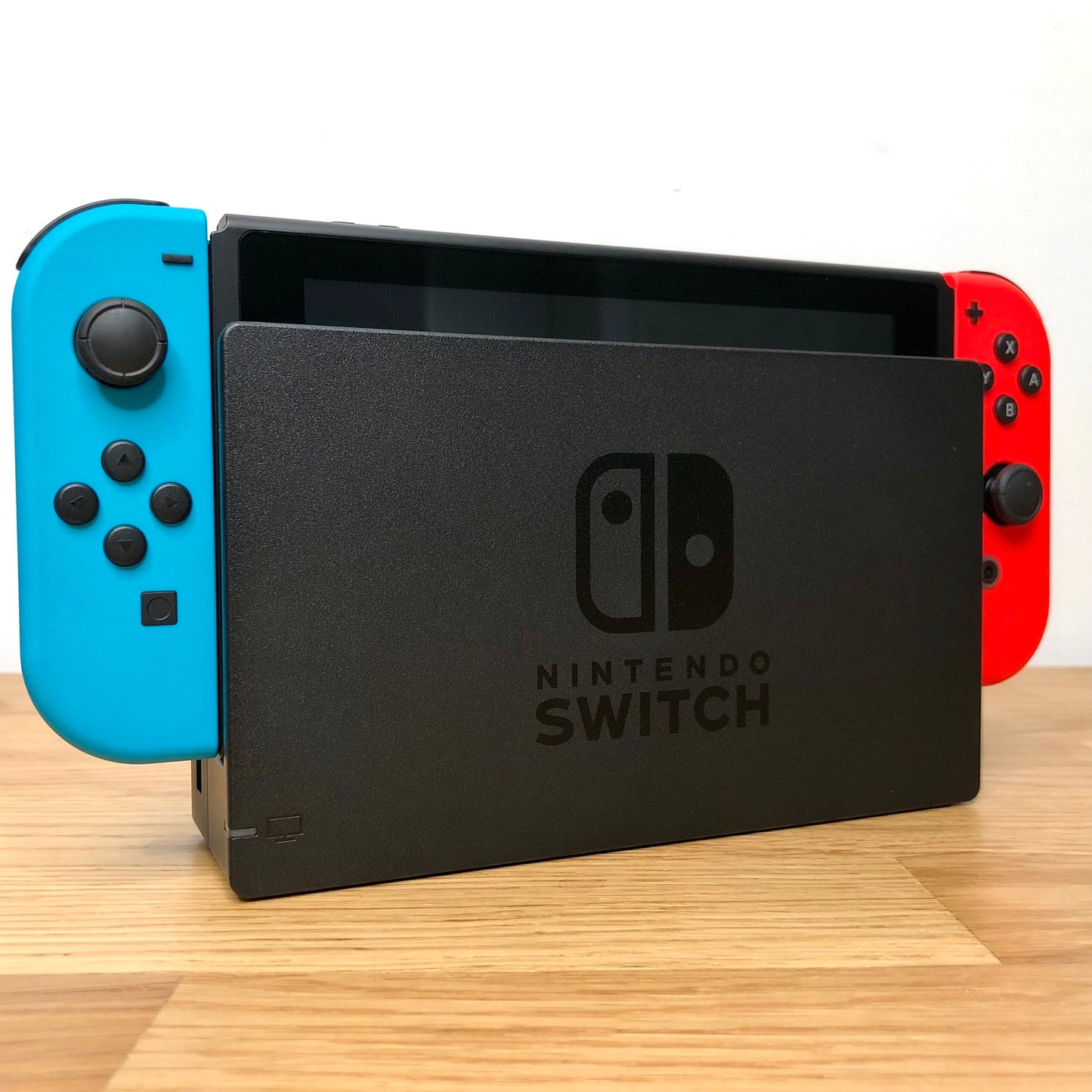 Angled left view of Nintendo Switch console docked with neon Joy-Cons, showing control sticks and front layout.