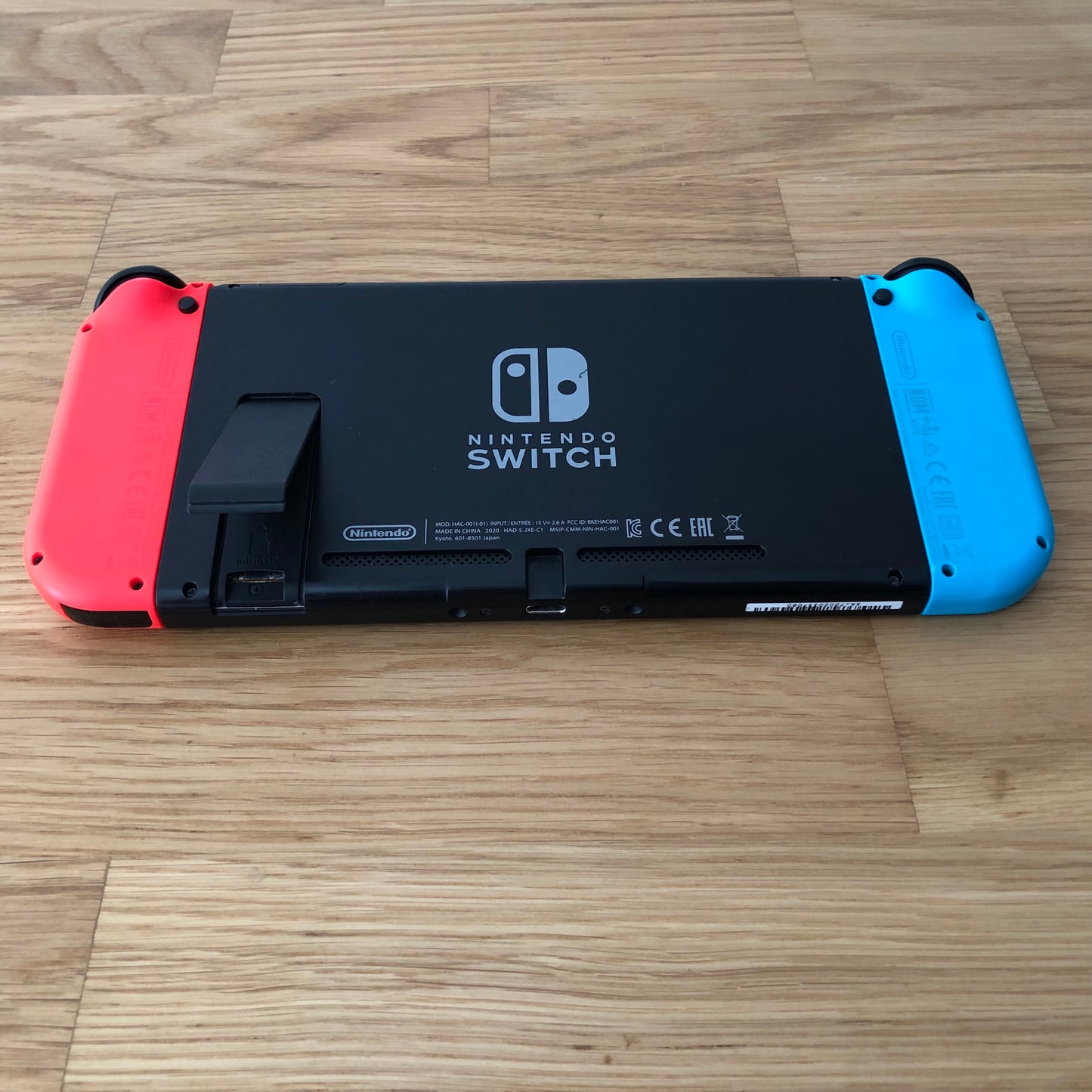 Rear of Nintendo Switch with kickstand open, showing logo, microSD card slot and dock connector.