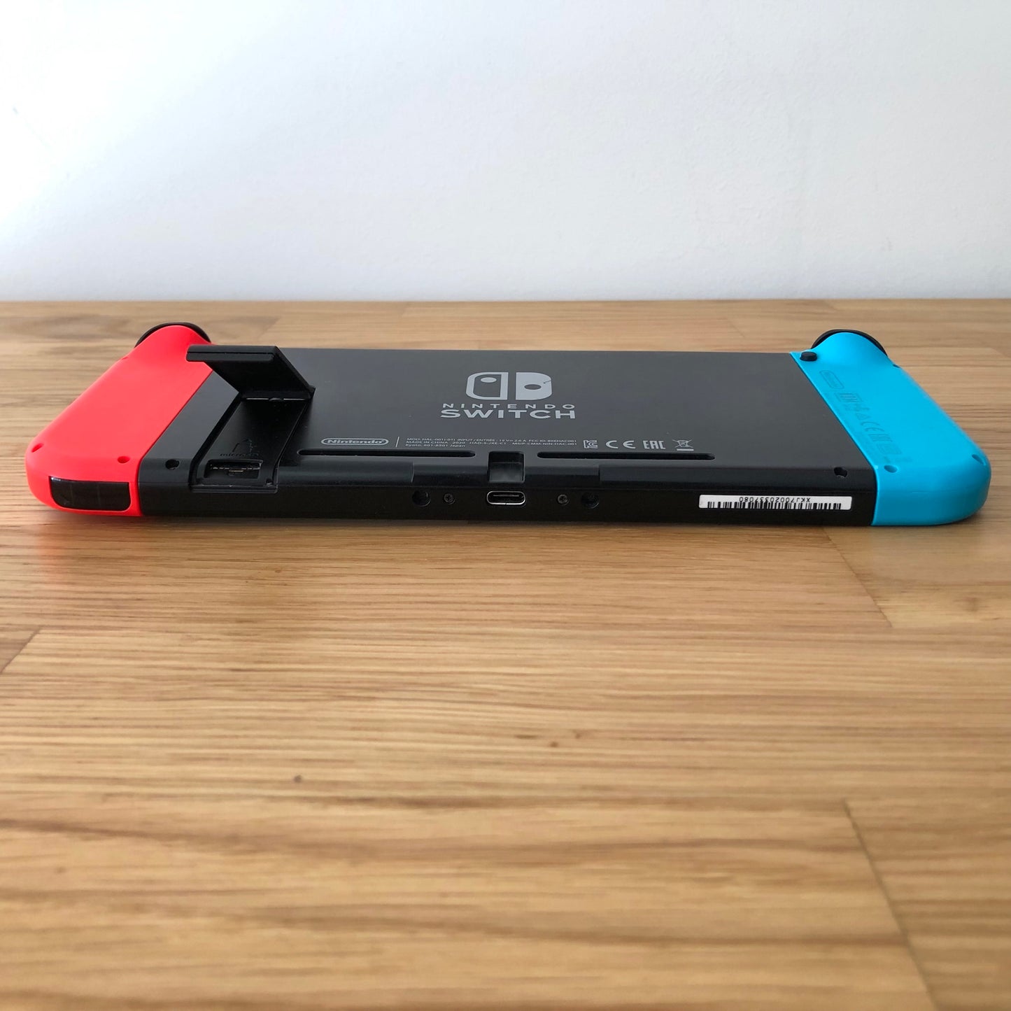 Rear of Nintendo Switch with kickstand open, showing logo, microSD card slot and dock connector.
