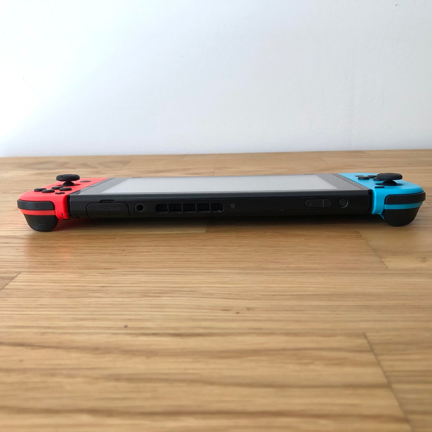 Top edge view of Nintendo Switch showing volume, power, card slot and shoulder bumpers with Joy-Cons attached.