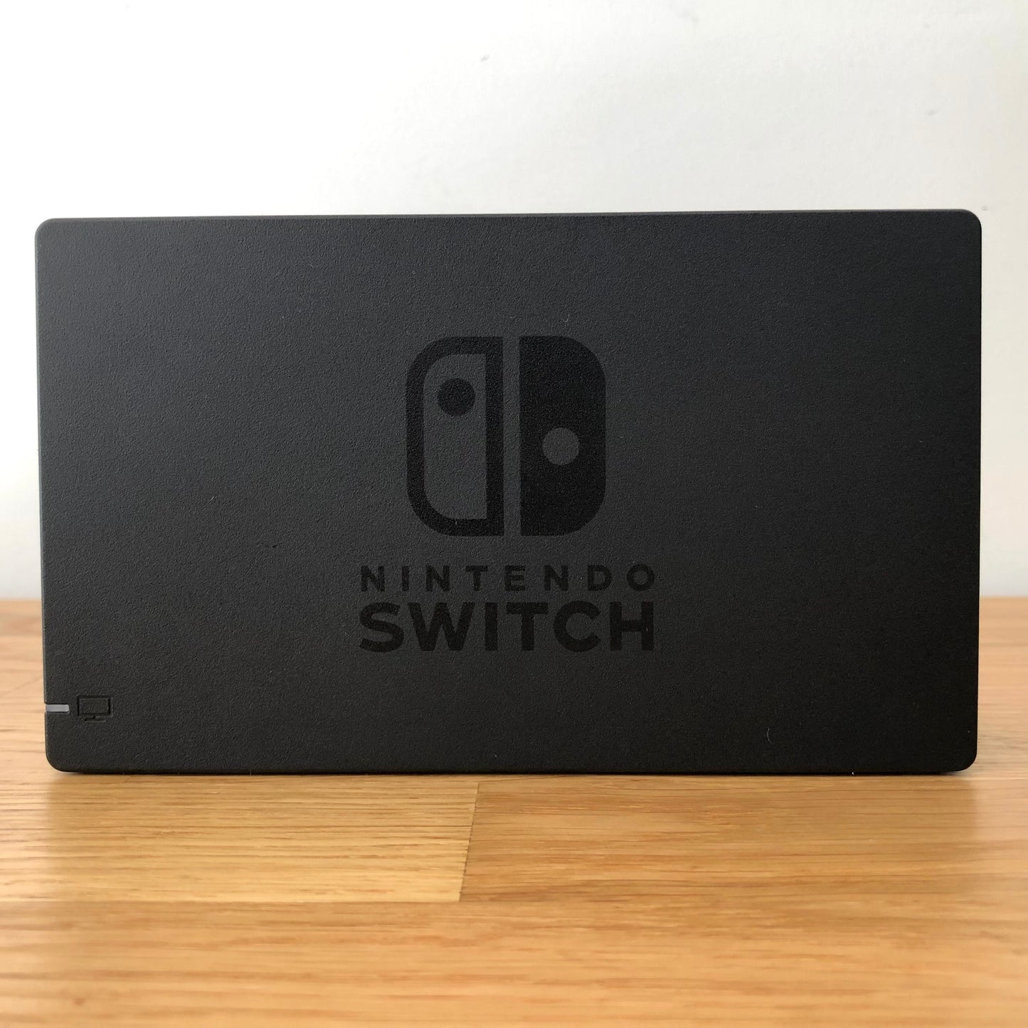 Front of Nintendo Switch dock with embossed logo, smooth matte finish and rounded edges, compatible with neon Joy-Cons.