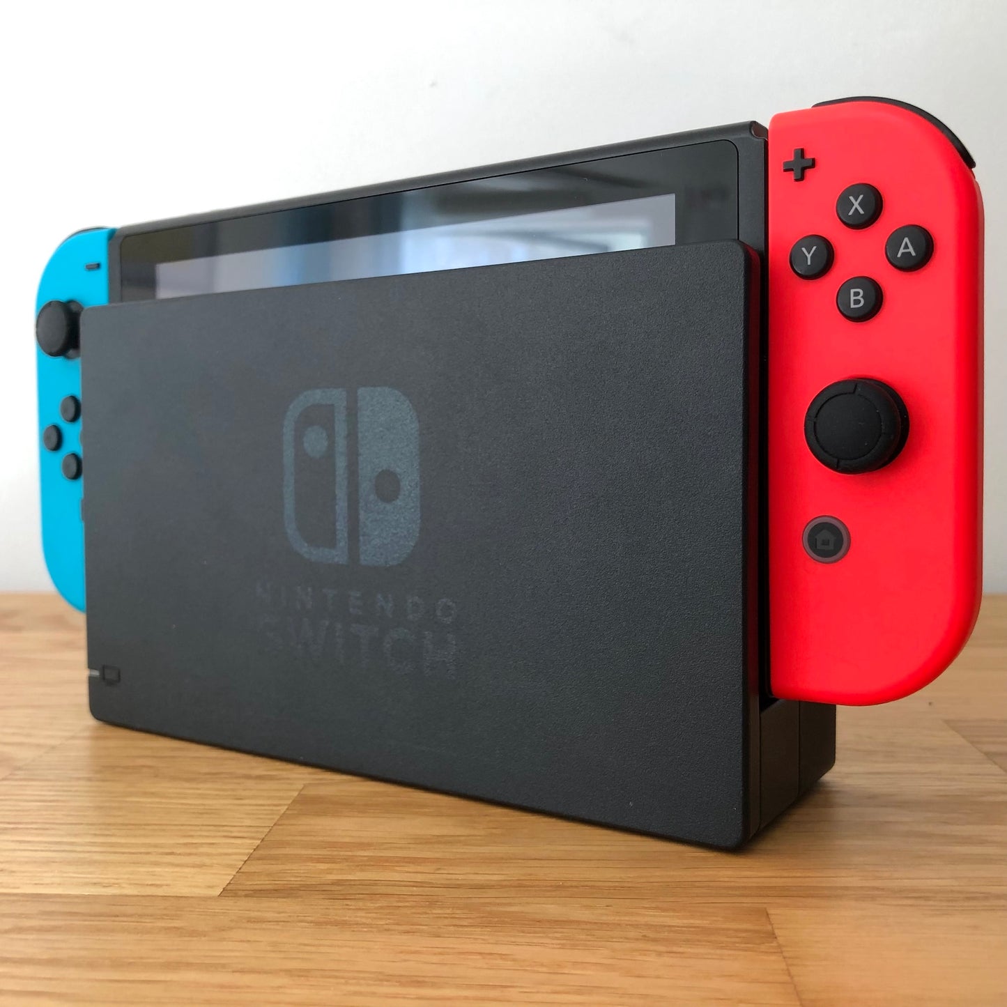 Angled right view of Nintendo Switch console docked with neon Joy-Cons, showing control sticks and front layout.