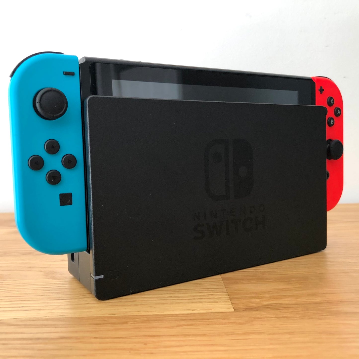 Angled left view of Nintendo Switch console docked with neon Joy-Cons, showing control sticks and front layout.