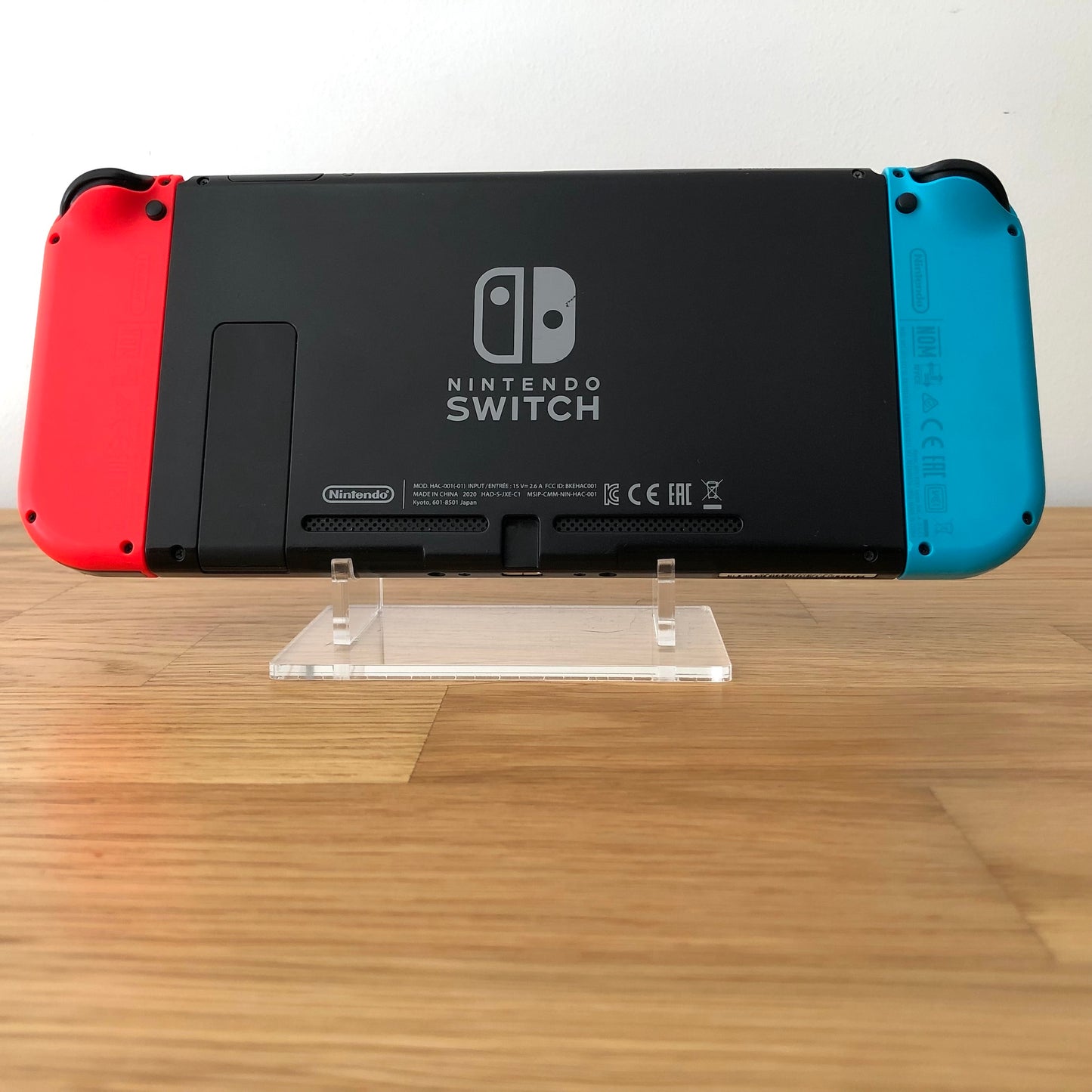 Back of Nintendo Switch console with red and blue Joy-Cons attached, showing logo, kickstand and trigger buttons.