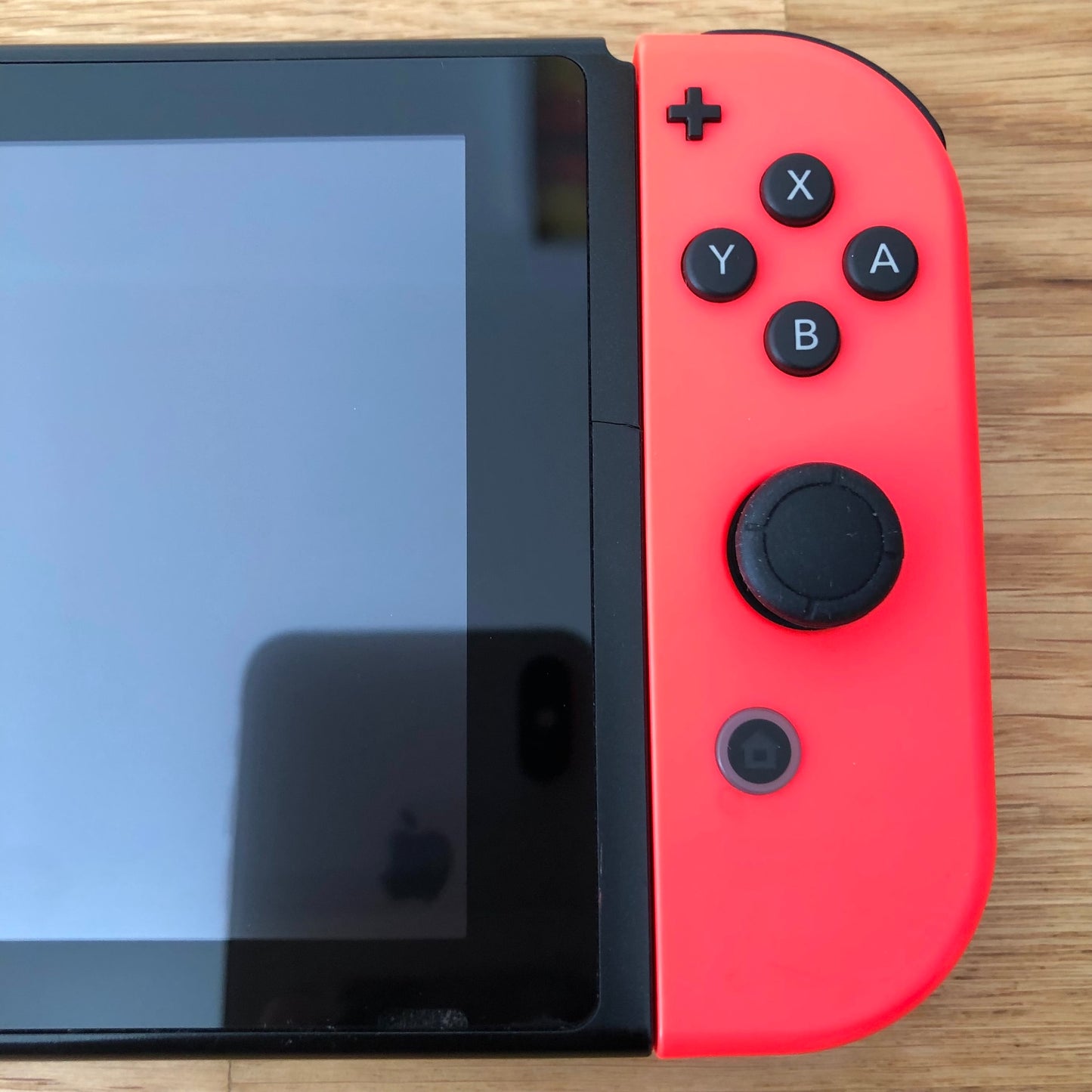 Close-up of neon red right Joy-Con on Nintendo Switch, showing A, B, X, Y buttons, stick, plus and home button.