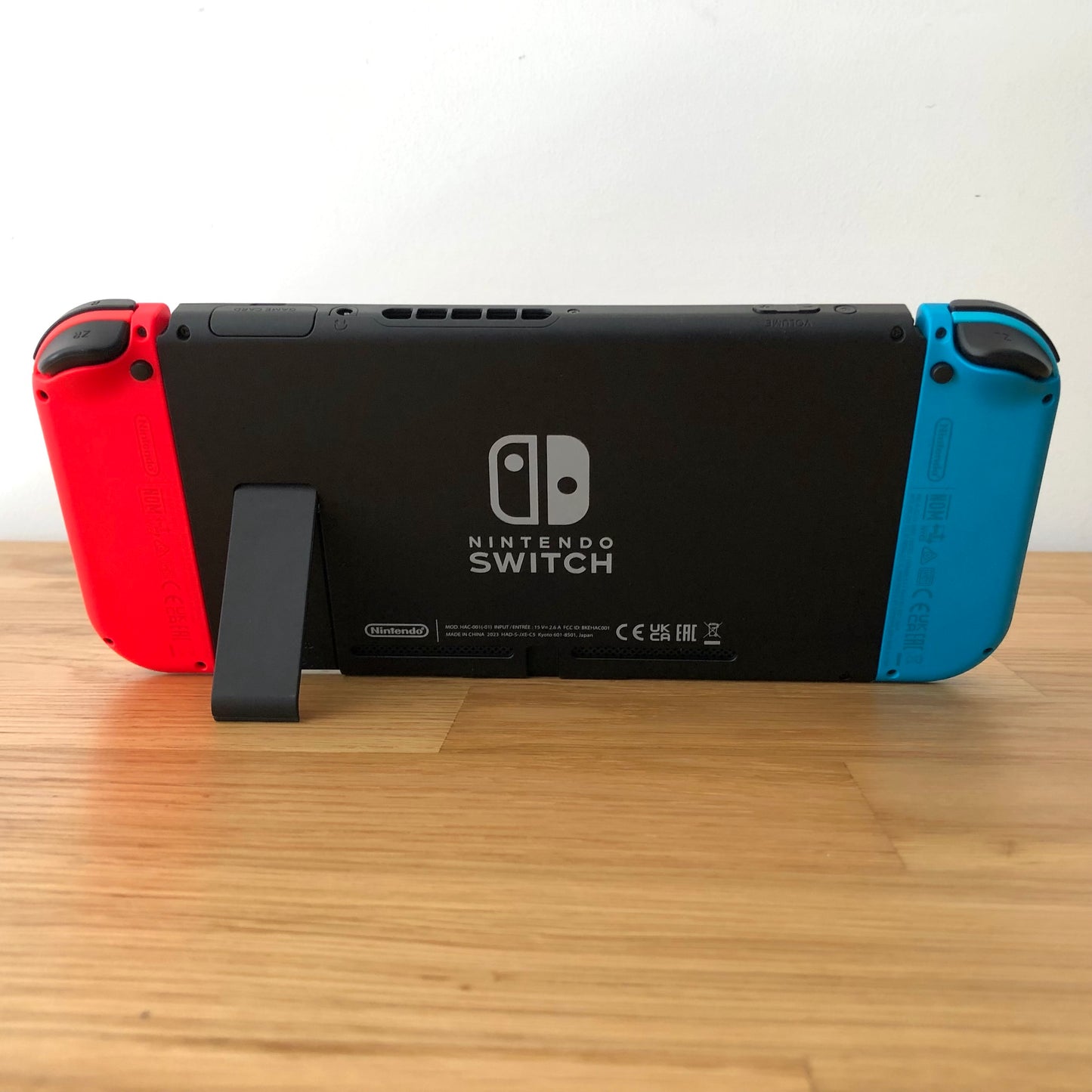 Back of Nintendo Switch console with Joy-Cons attached, showing logo, serial info, triggers and kickstand opened.