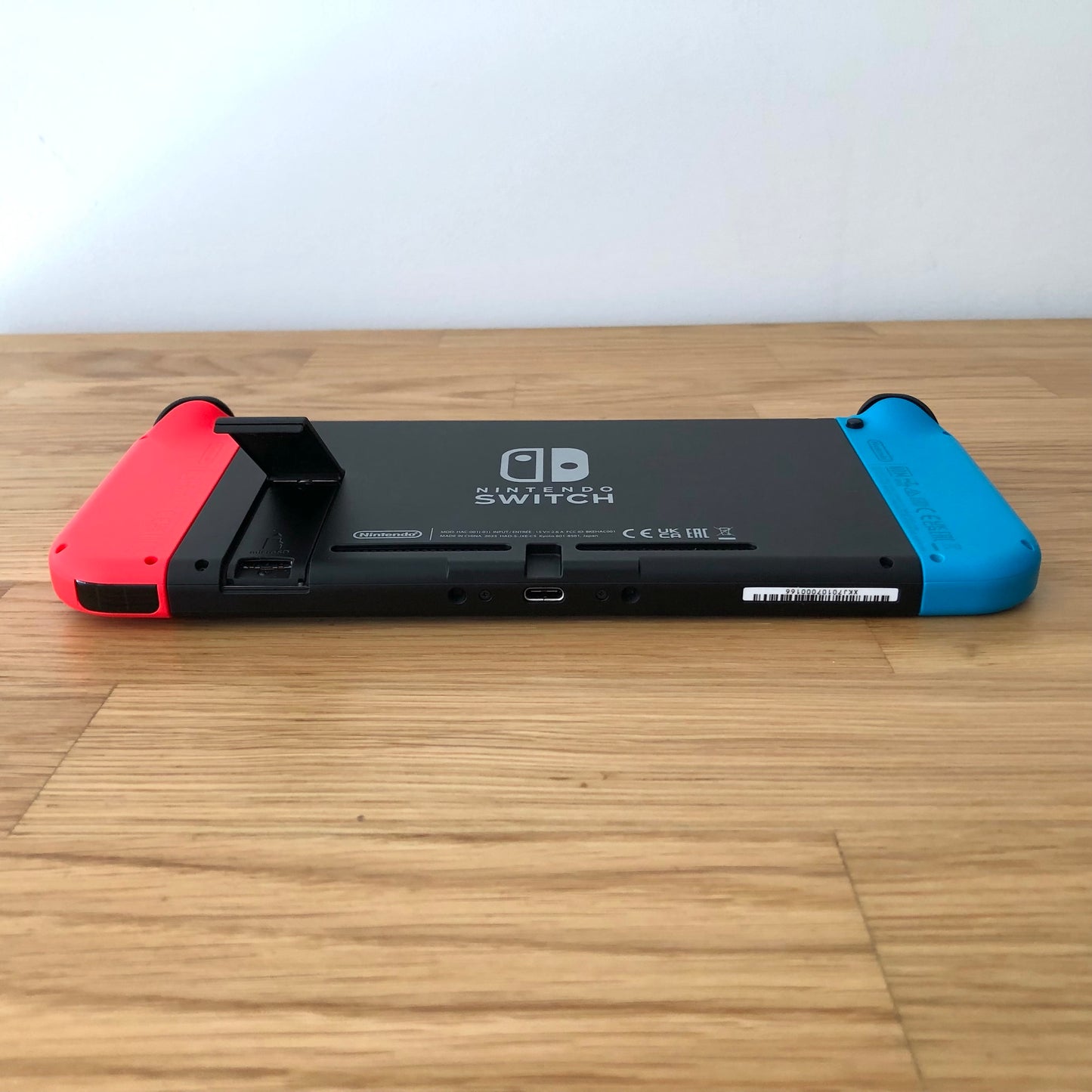 Rear of Nintendo Switch with kickstand open, showing logo, microSD card slot and dock connector.