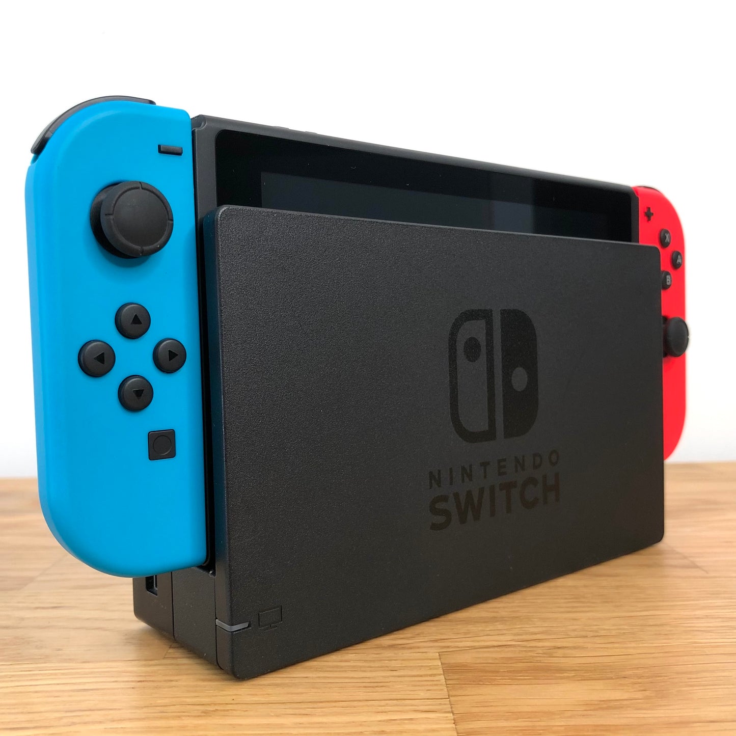 Angled left view of Nintendo Switch console docked with neon Joy-Cons, showing control sticks and front layout.