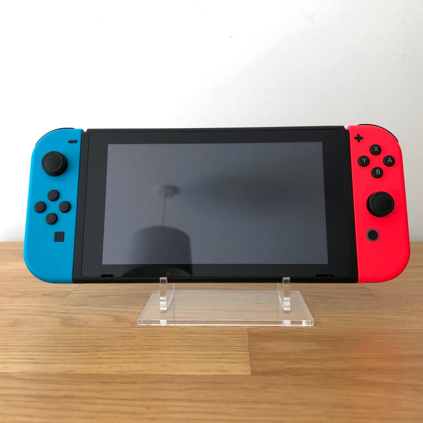 Front view of Nintendo Switch console with red and blue Joy-Cons attached, showing screen and face button layout.