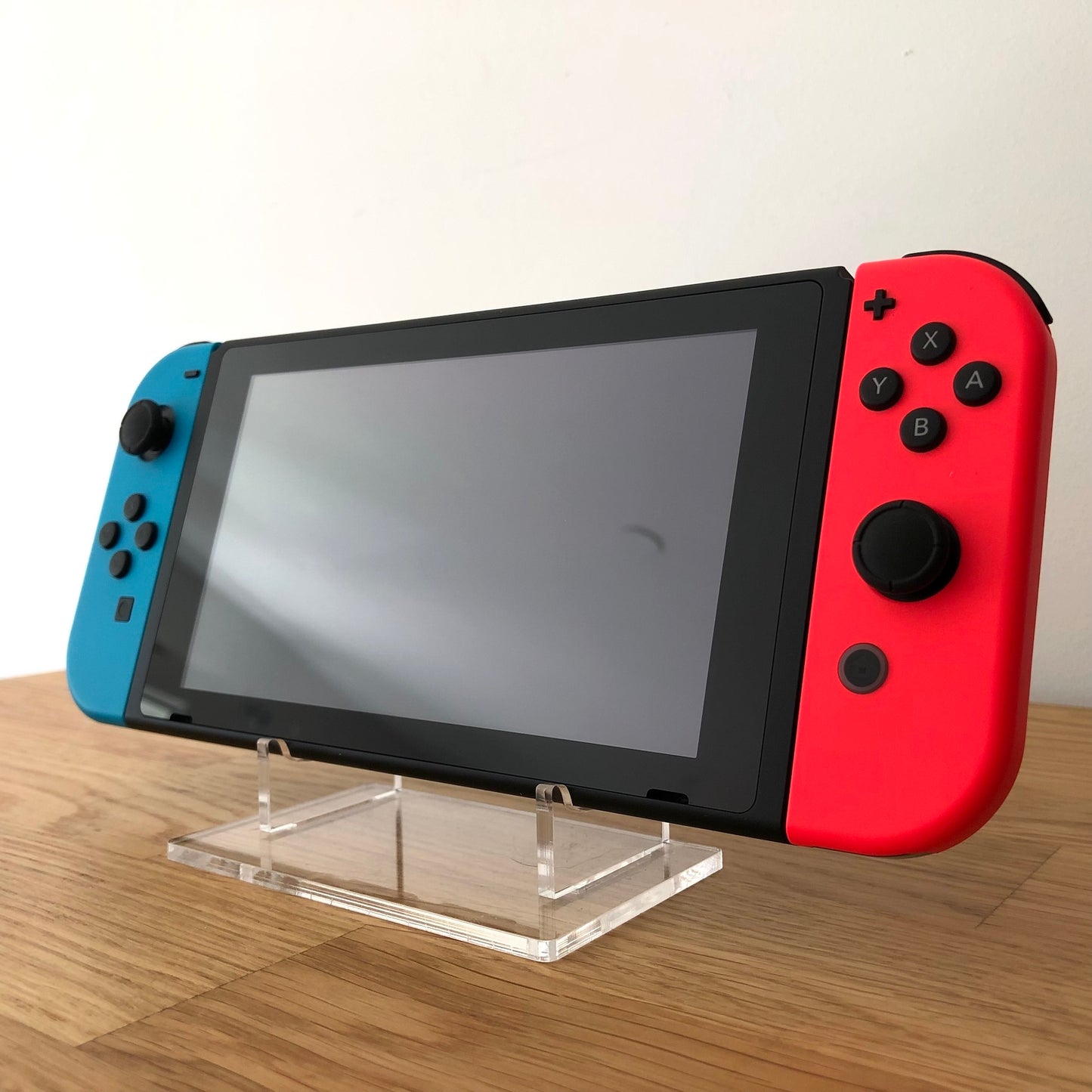 Angled front of Nintendo Switch with neon Joy-Cons, showing full face buttons, control sticks and screen.