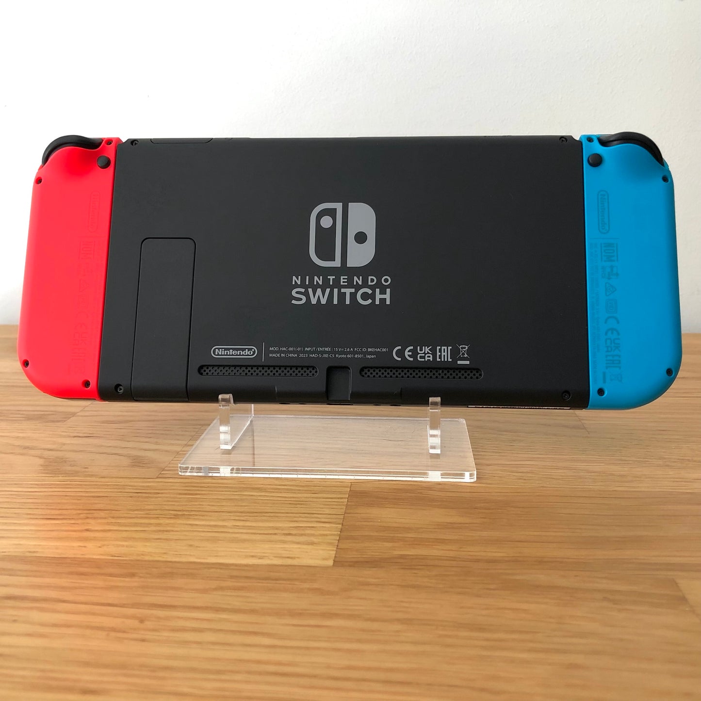 Back of Nintendo Switch console with red and blue Joy-Cons attached, showing logo, kickstand and trigger buttons.