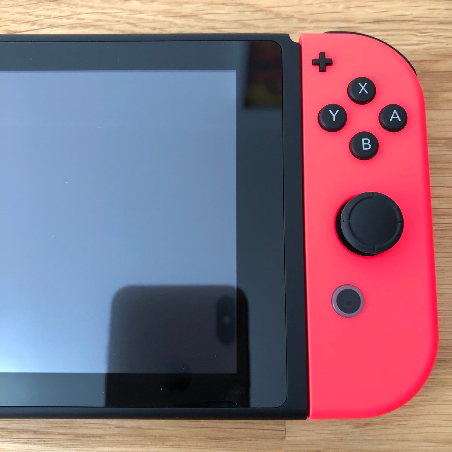 Close-up of neon red right Joy-Con on Nintendo Switch, showing A, B, X, Y buttons, stick, plus and home button.