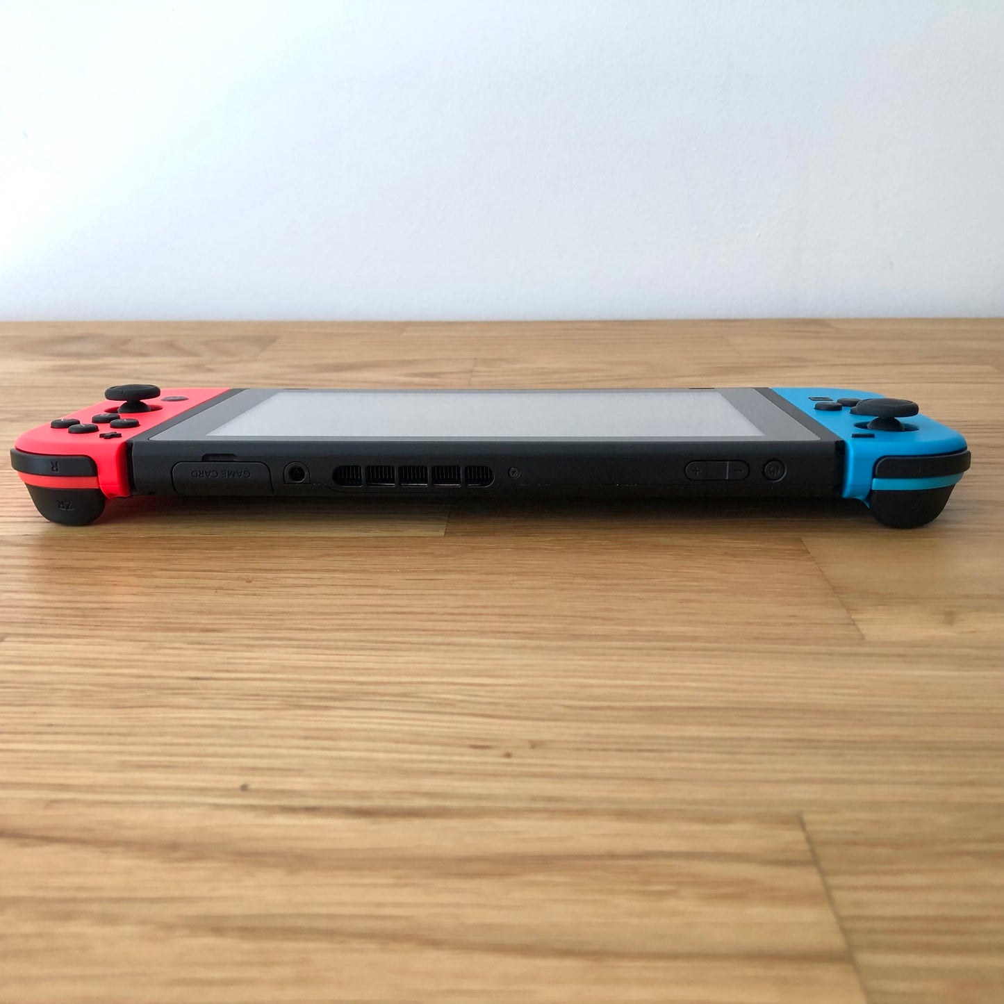 Top edge view of Nintendo Switch showing volume, power, card slot and shoulder bumpers with Joy-Cons attached.