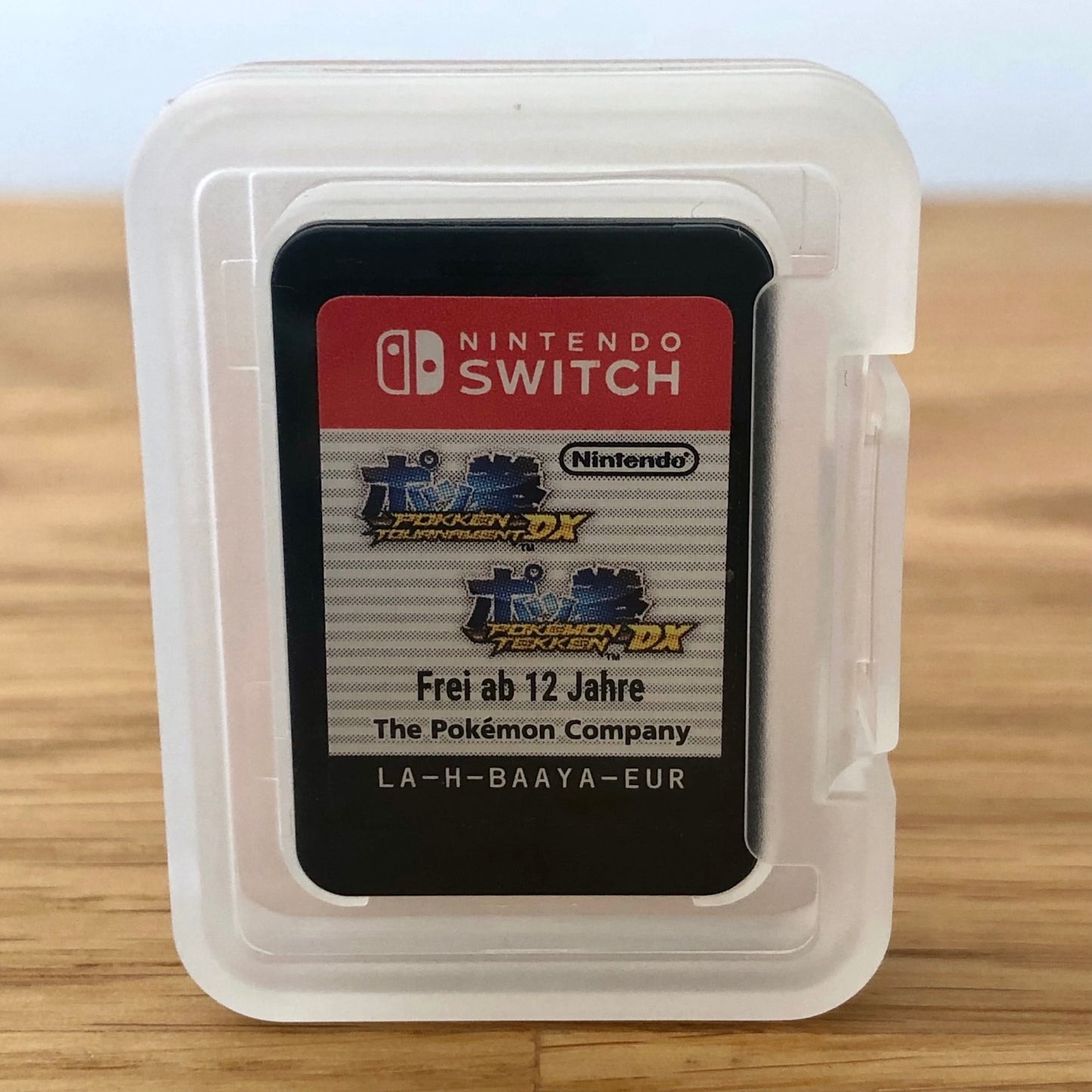 Pokkén Tournament DX Nintendo Switch cartridge inside a transparent protective case, showing the front label through the plastic.