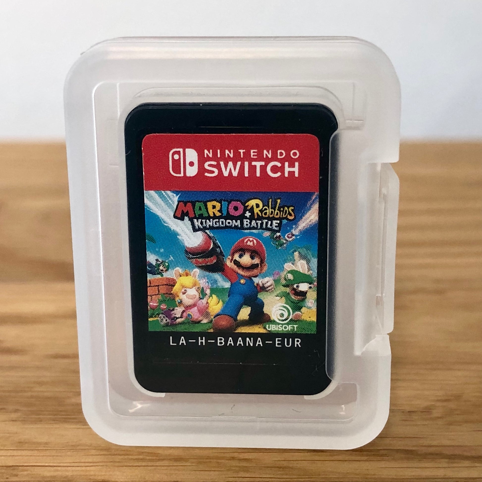 Cartridge of Mario + Rabbids Kingdom Battle for Nintendo Switch, the cartridge is inside a cartridge size transparent protective case, through which you can see the front of the cartridge