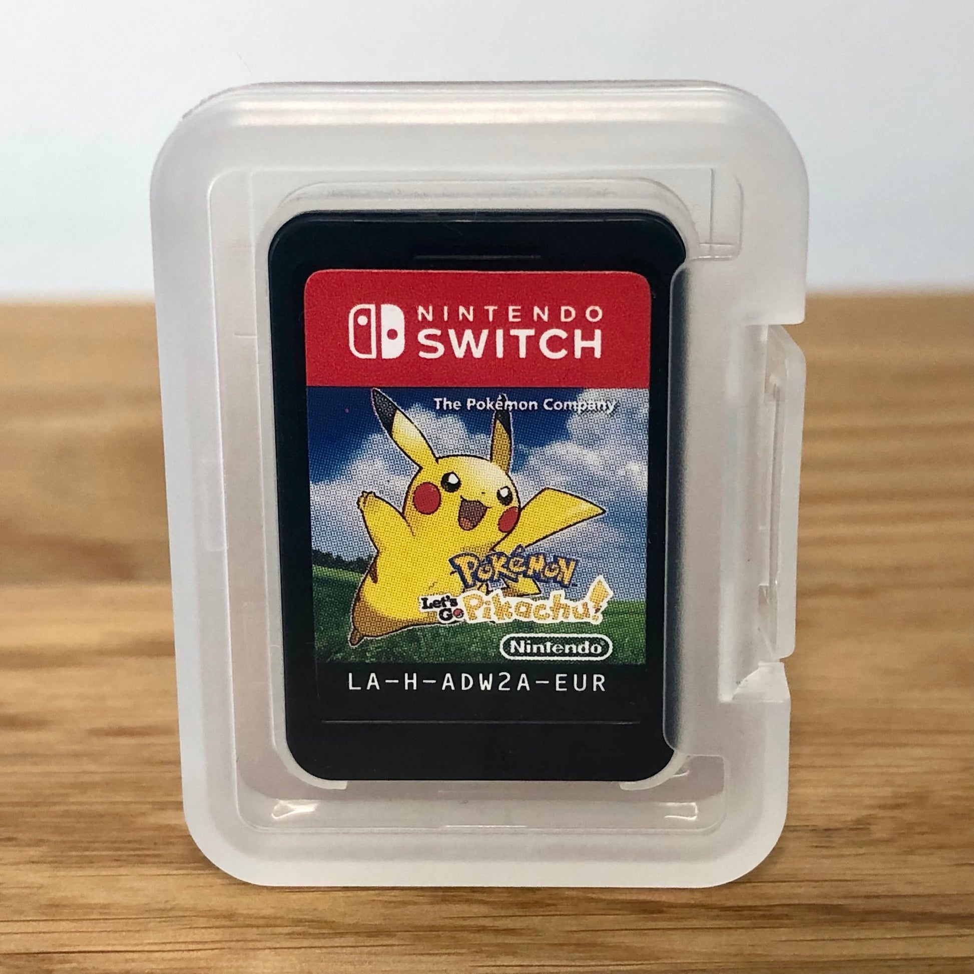 Cartridge of Pokémon: Let’s go Pikachu for Nintendo Switch, the cartridge is inside a cartridge size transparent protective case, through which you can see the front of the cartridge