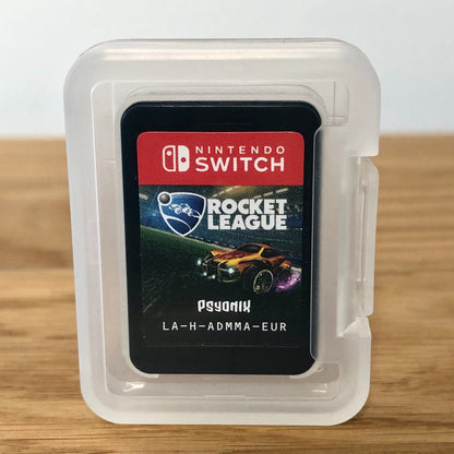 Cartridge of Rocket League for Nintendo Switch, the cartridge is inside a cartridge size transparent protective case, through which you can see the front of the cartridge