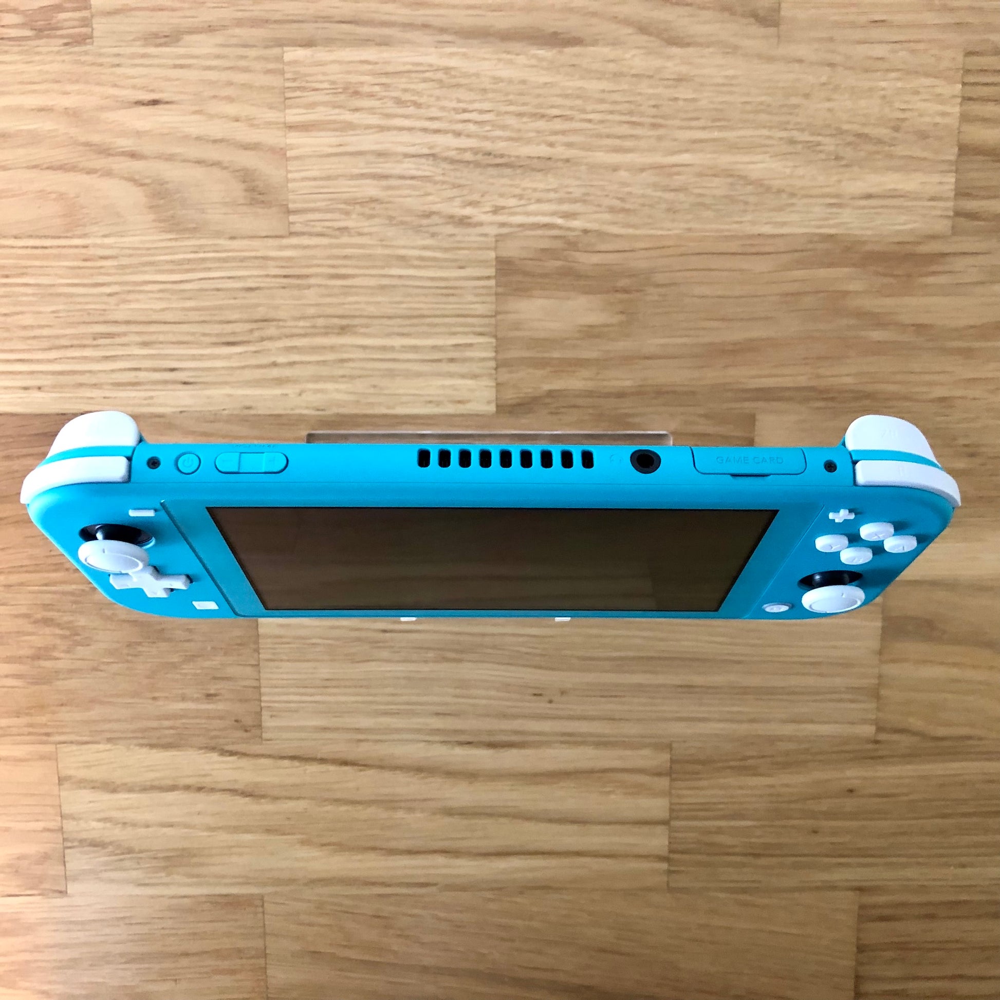 Top view of Turquoise Nintendo Switch Lite console showing volume, power, headphone jack and game card slot.