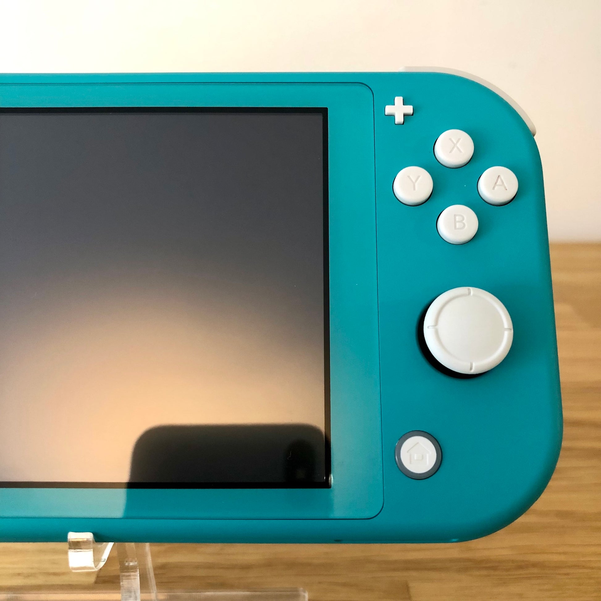 Close-up of right side controls on Turquoise Nintendo Switch Lite including A, B, X, Y and home button.