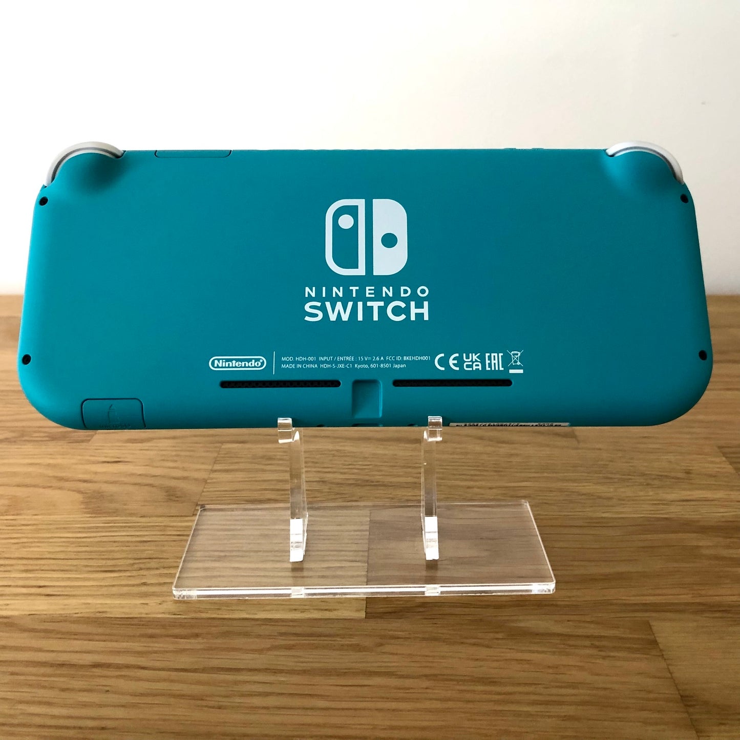 Rear view of Turquoise Nintendo Switch Lite console on stand, showing Nintendo Switch branding and condition.