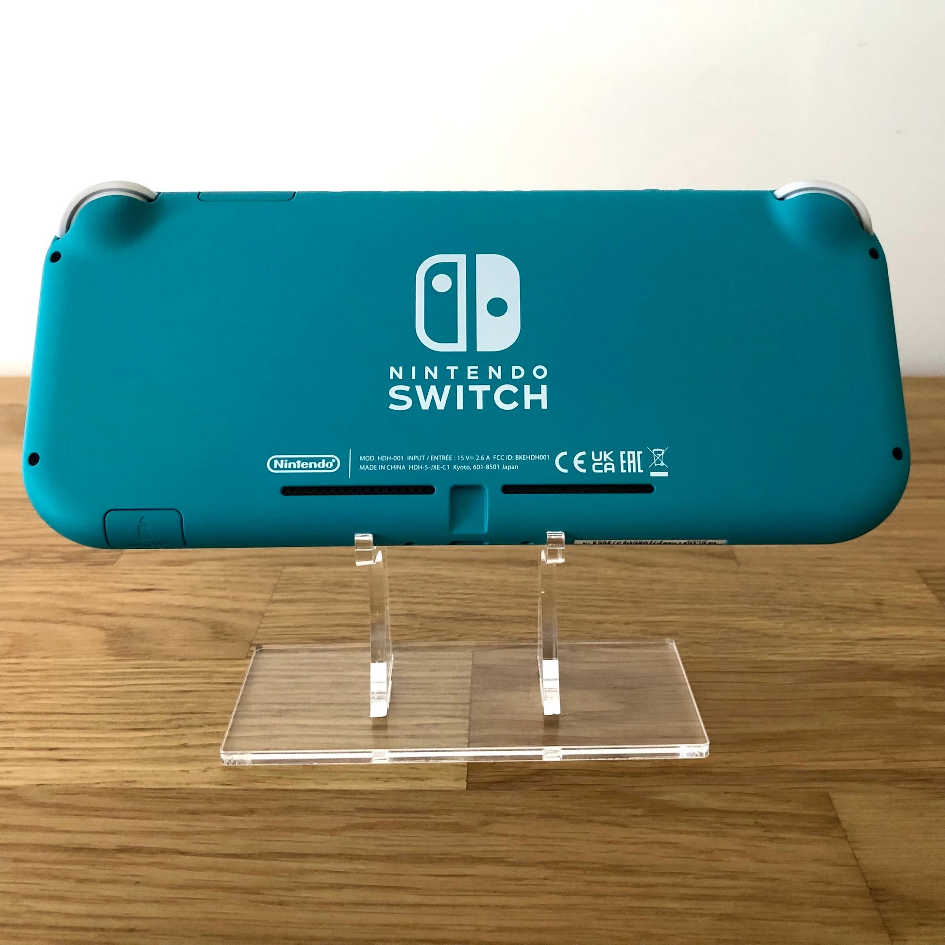 Rear view of Turquoise Nintendo Switch Lite console on stand, showing Nintendo Switch branding and condition.