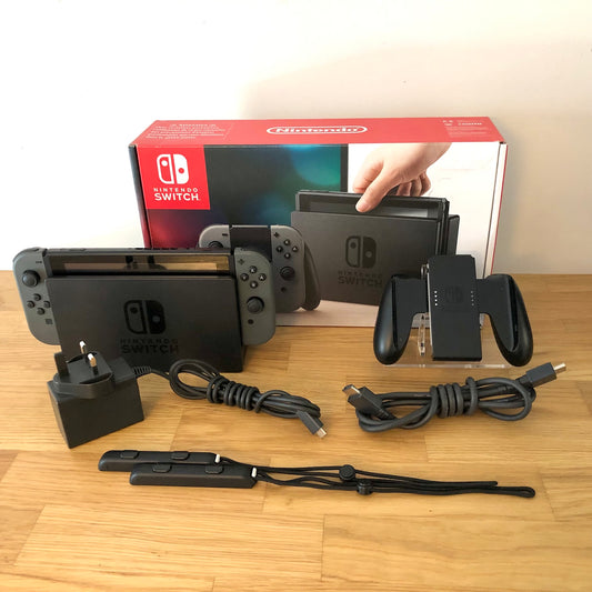 Grey Nintendo Switch console with original box, Joy-Con grip, charger, HDMI cable and wrist straps shown.