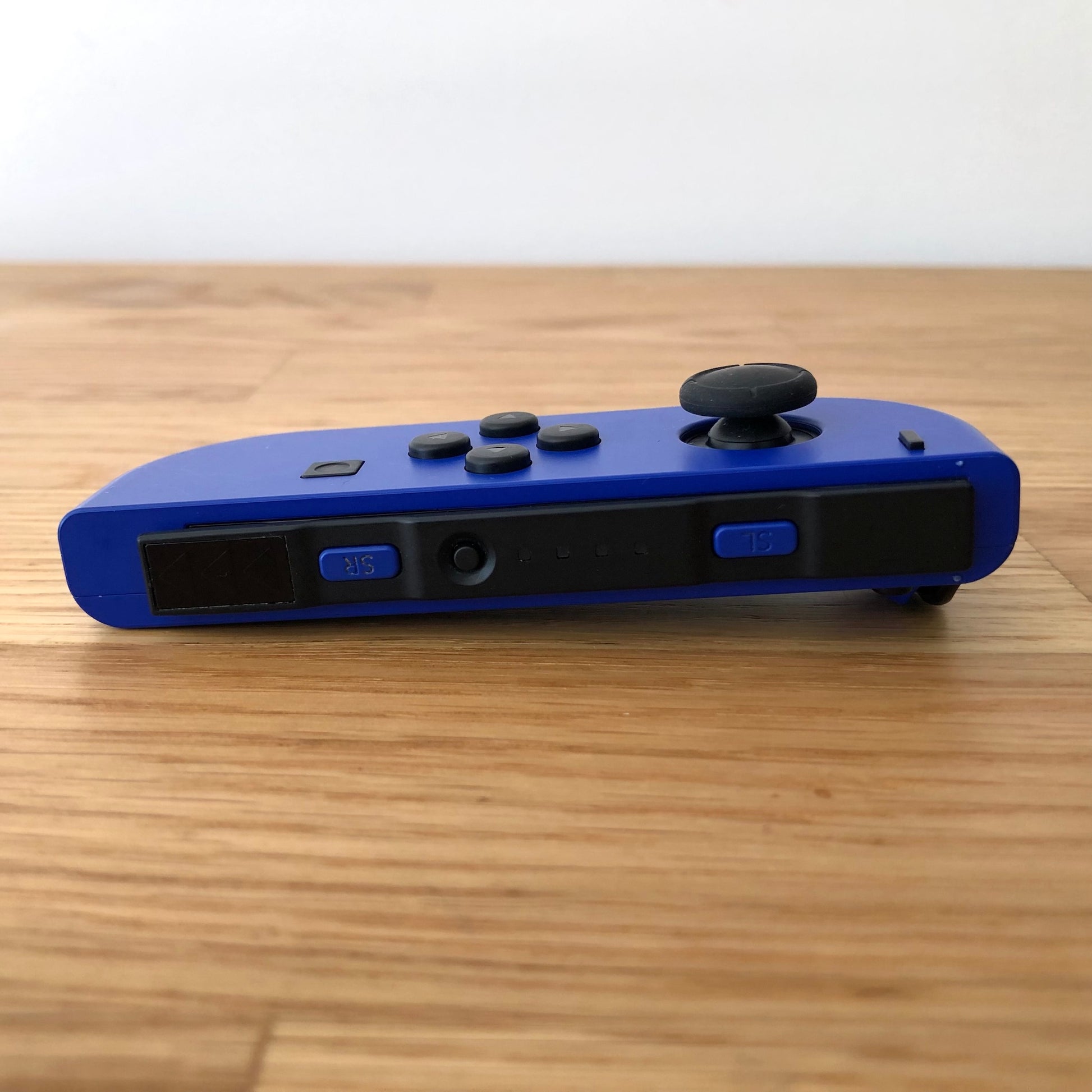 Bottom side view of neon blue Nintendo Switch Joy-Con controller displaying SL, SR, and sync button.