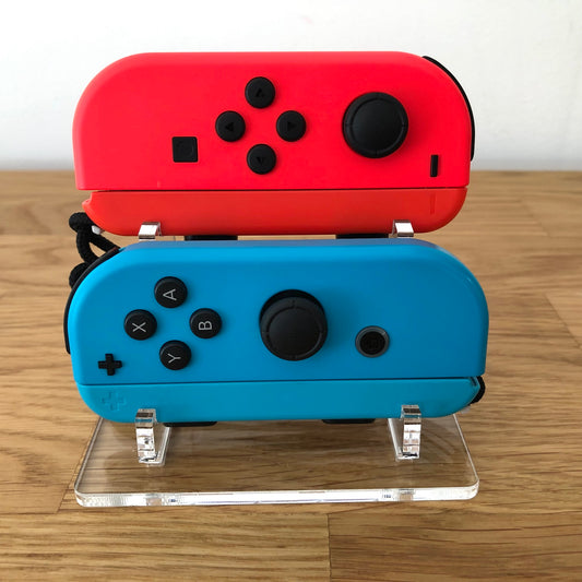 Front view of neon red and blue Nintendo Switch Joy-Con controllers displayed on a clear stand.