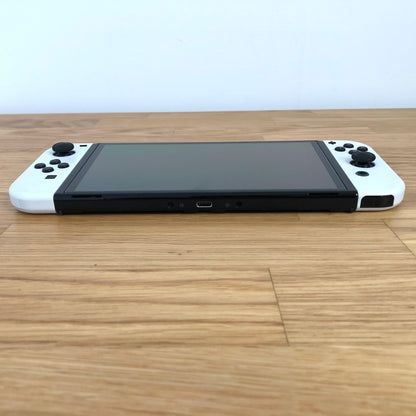 Bottom edge of Nintendo Switch OLED console showing USB-C charging port and Joy-Cons attached.