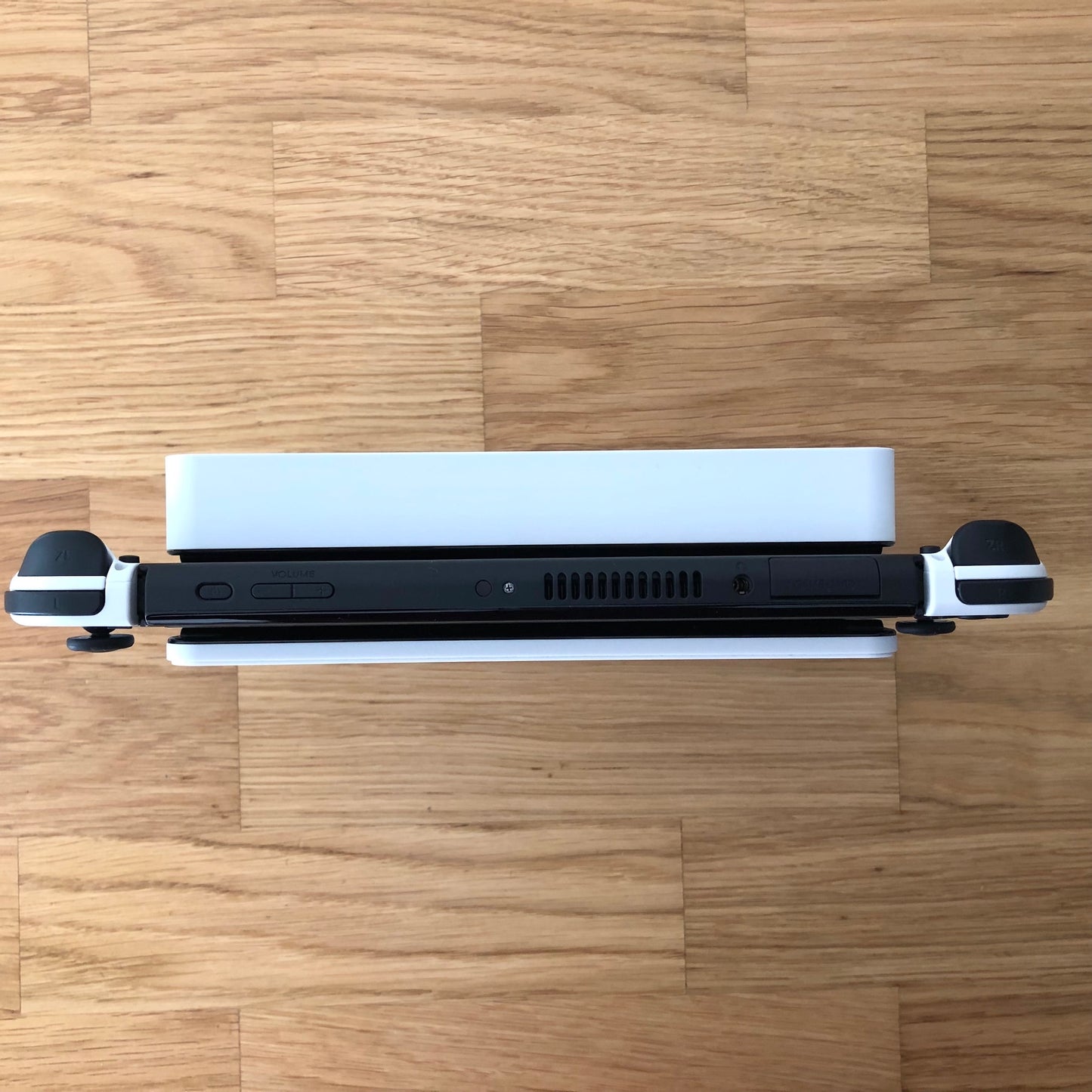 Top-down view of Nintendo Switch OLED in dock, showing Joy-Con triggers, game card slot and top-side buttons.