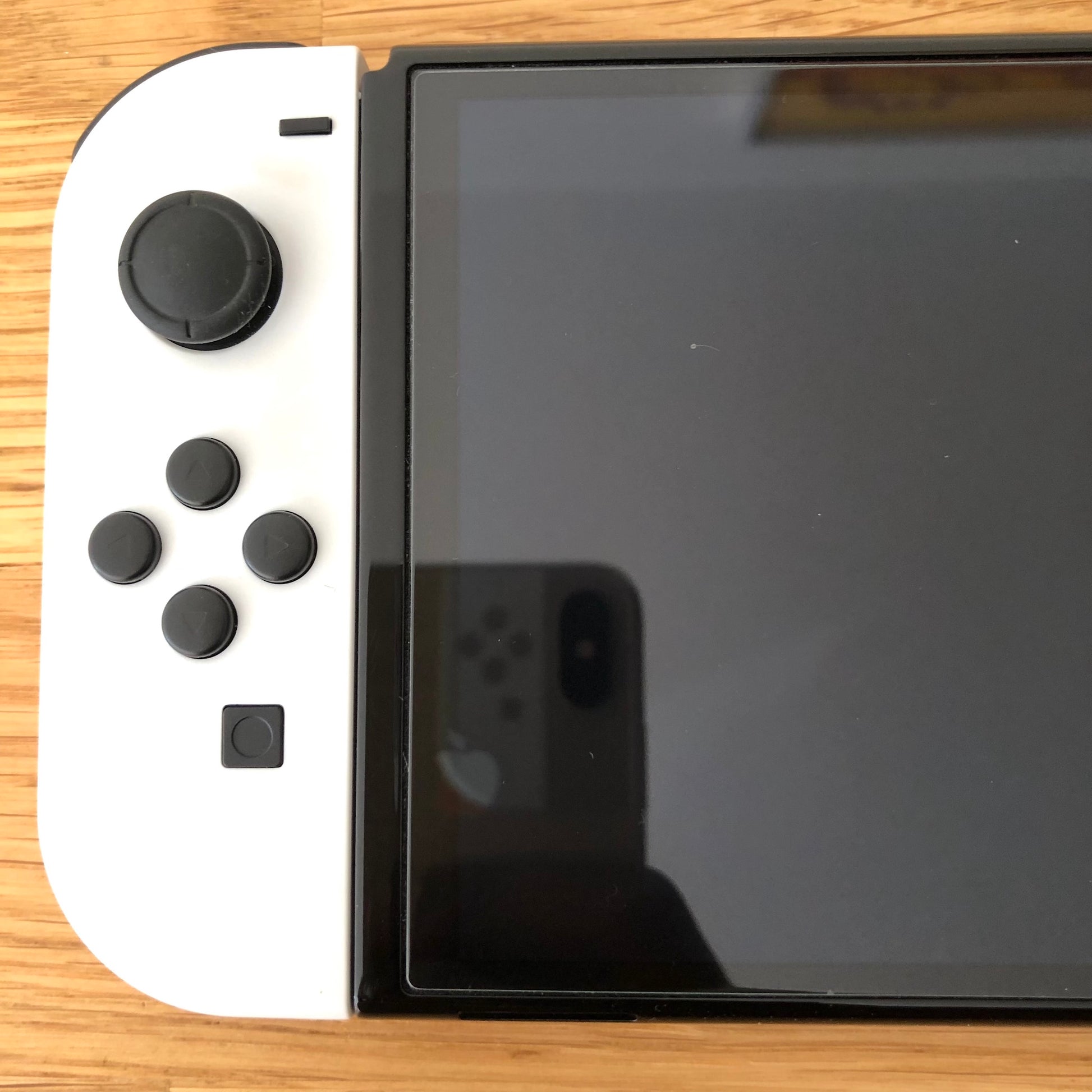 Close-up of left side of Nintendo Switch OLED screen with white Joy-Con showing control stick and buttons.