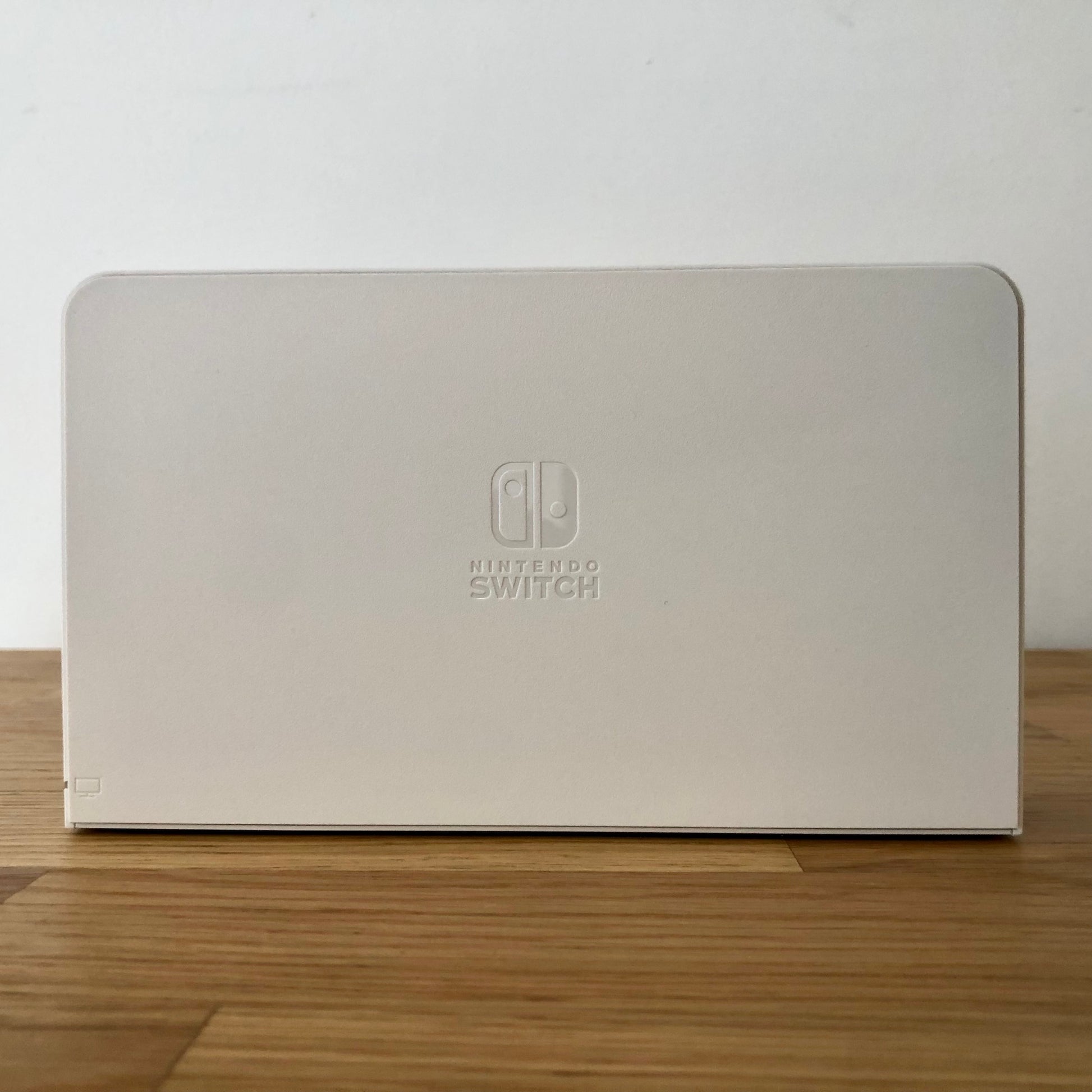 Front of white Nintendo Switch OLED dock with embossed Nintendo Switch logo, smooth matte finish and rounded edges.