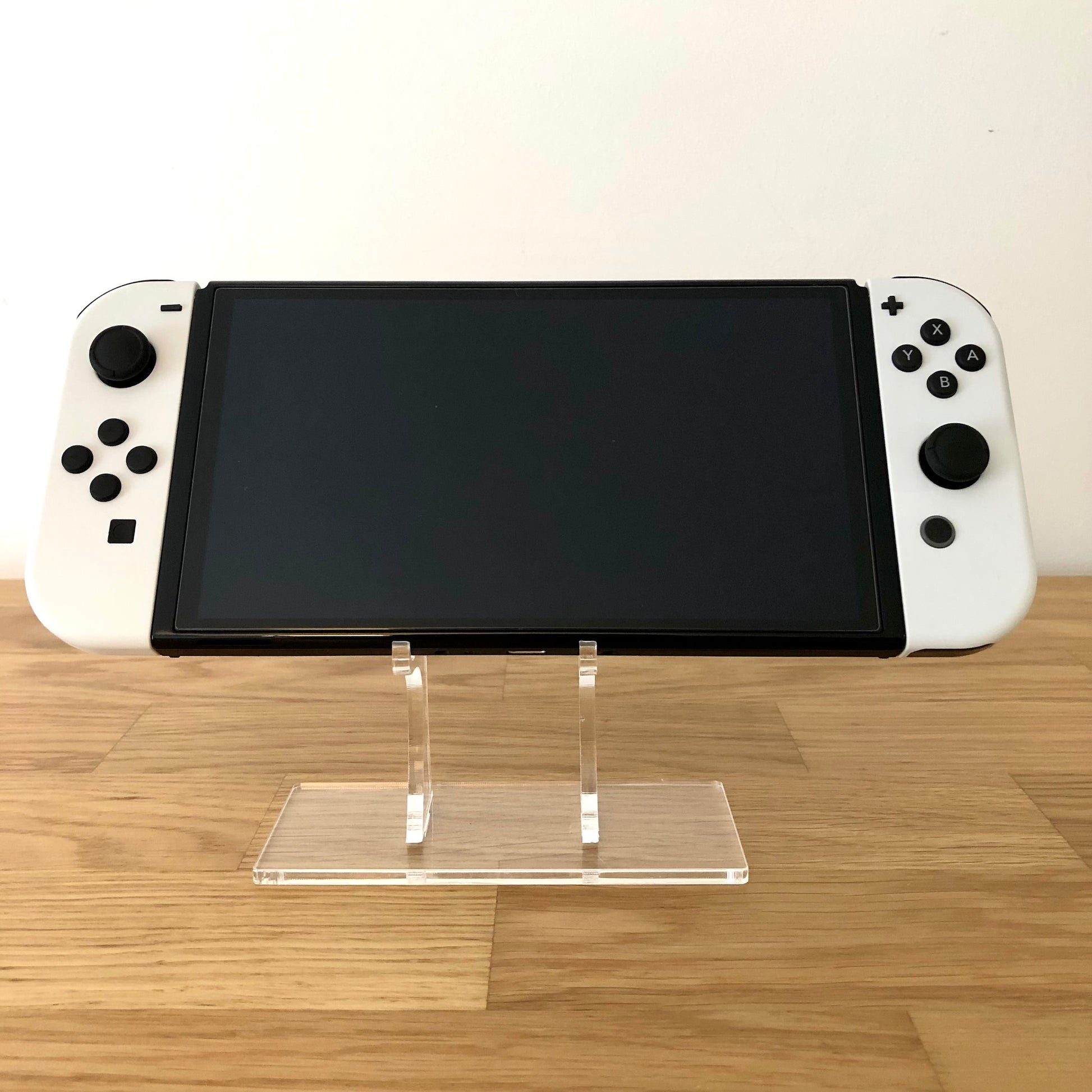 Front view of Nintendo Switch OLED console with white Joy-Cons attached, screen off, showing condition and displaying all front buttons.
