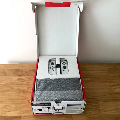 Nintendo Switch OLED console in original box with top open, showing console and Joy-Cons neatly packed in protective tray