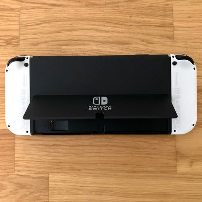 Back of Nintendo Switch OLED with kickstand open, showing logo, game card slot, vent and volume controls.
