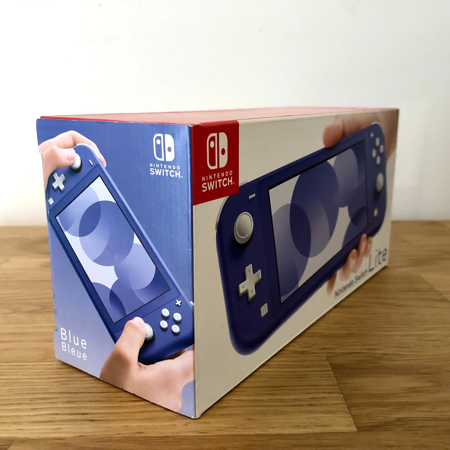 Side angle of Nintendo Switch Lite box in blue, showing product artwork and multilingual 'Blue/Bleue' label.