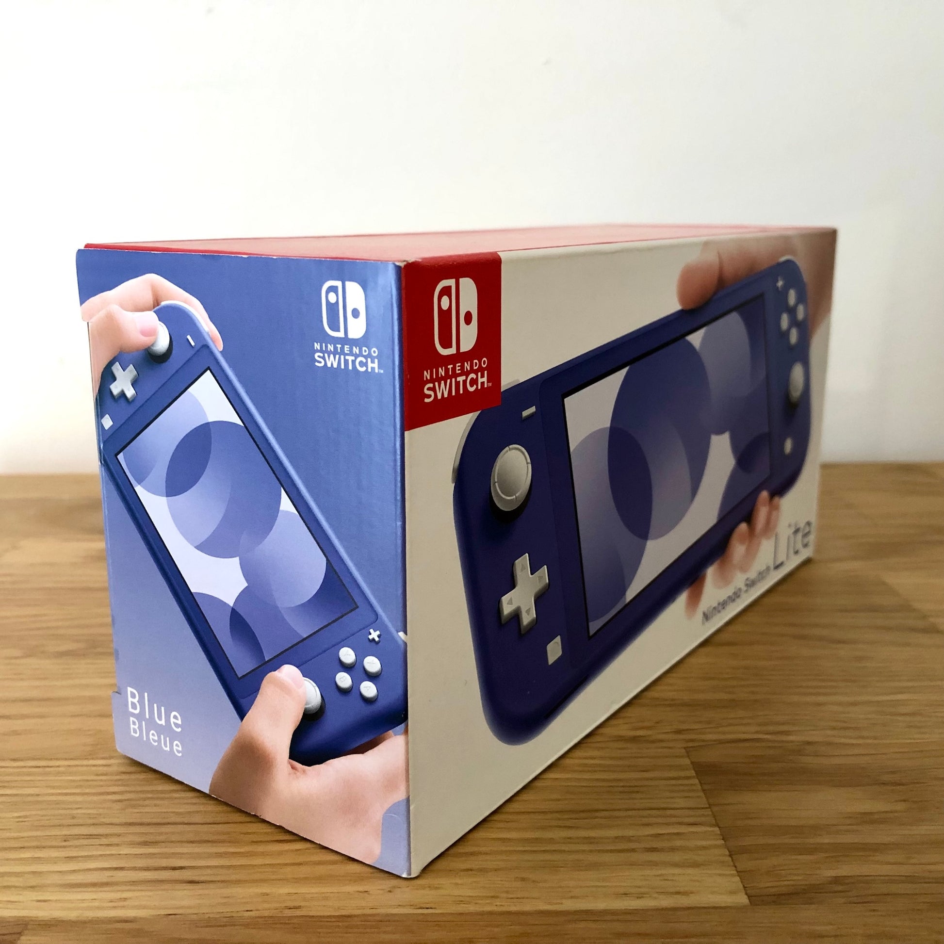Side angle of Nintendo Switch Lite box in blue, showing product artwork and multilingual 'Blue/Bleue' label.